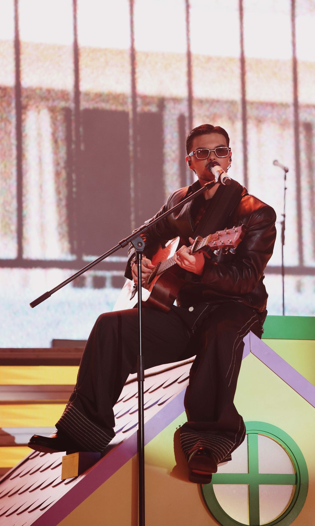 Abraham Mateo tocando guitarra y cantando en un escenario con casa de juguete.