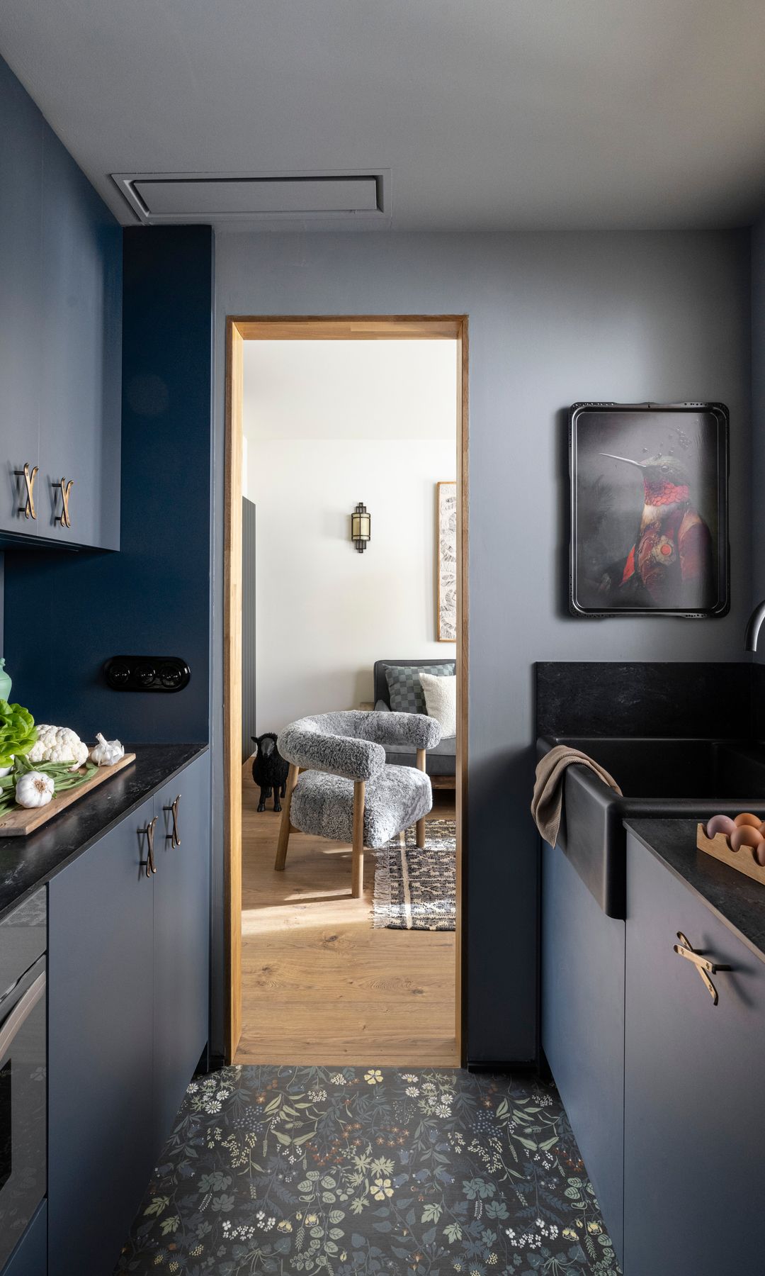 Cocina pequeña en azul marino con solo oscuro, encimera negra, cuadro en la pared