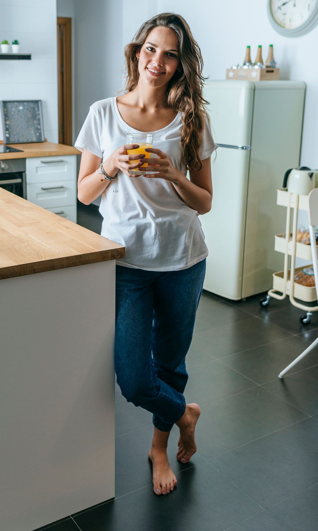 Mujer tomando un zumo de naranja en la cocina