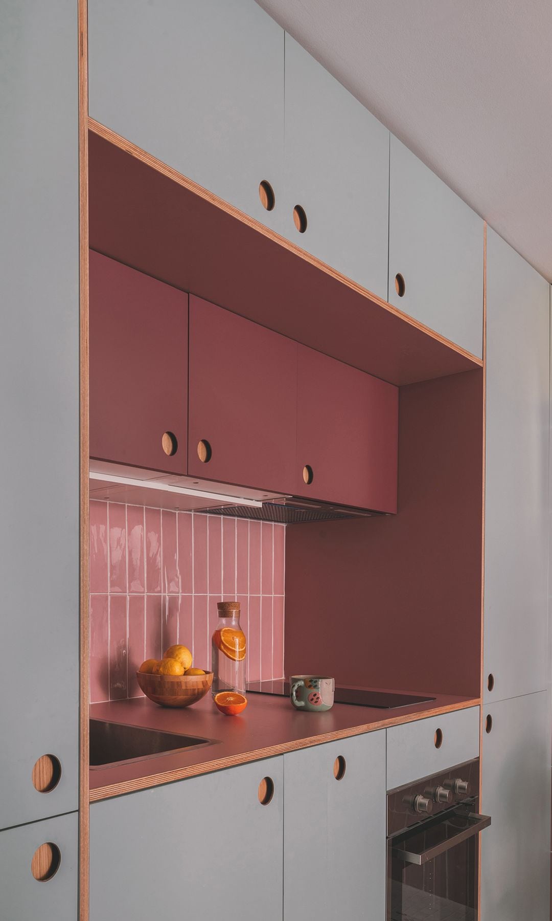 Cocina de IKEA en color azul claro, sin tiradores, armarios hasta el techo, azulejos rosas, encimera de madera, 