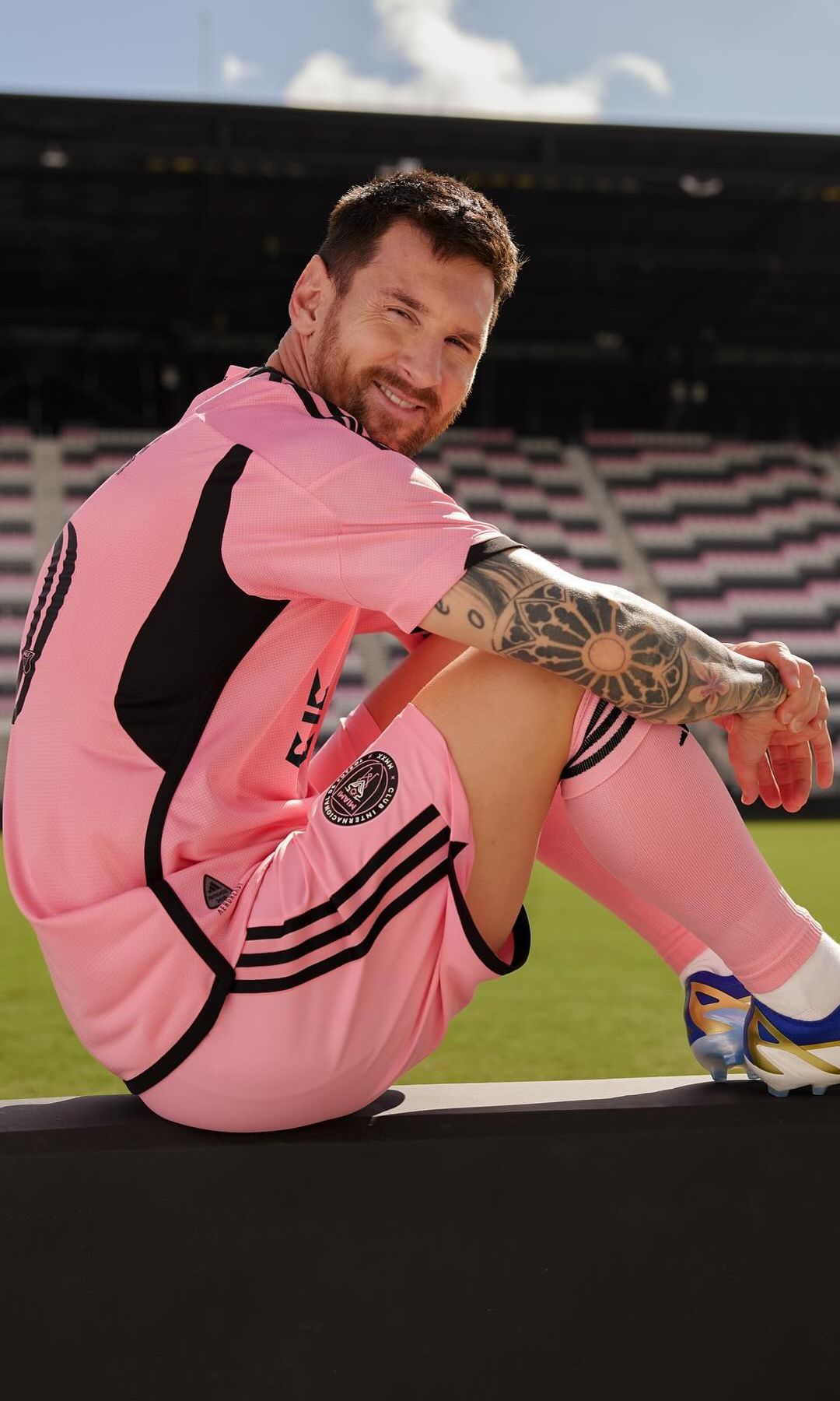 Leo Messi sentado a pie de campo con equipación rosa y sus nuevos botines de Adidas