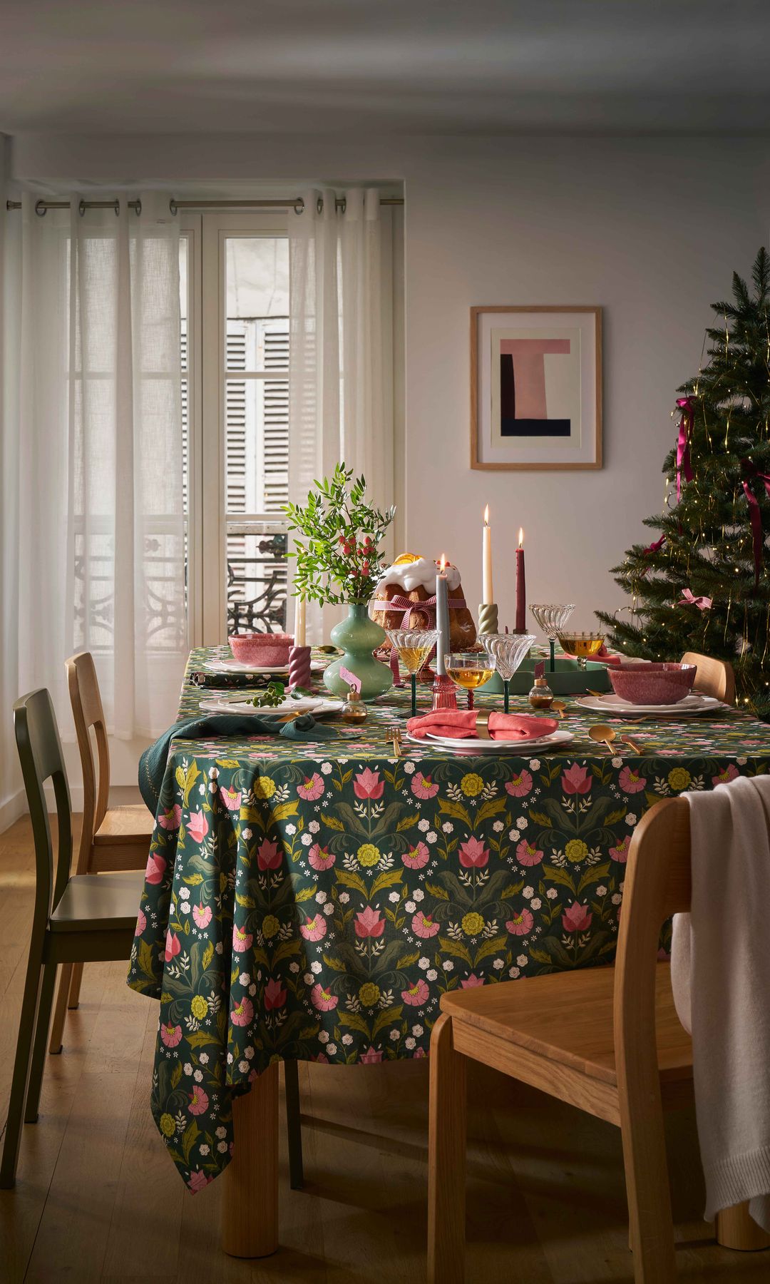 Mesa vestida de Navidad, árbol de Navidad, mantel verde estampado con flores rosas, velas, jarrón de cristal verde con arreglo verde y rosa
