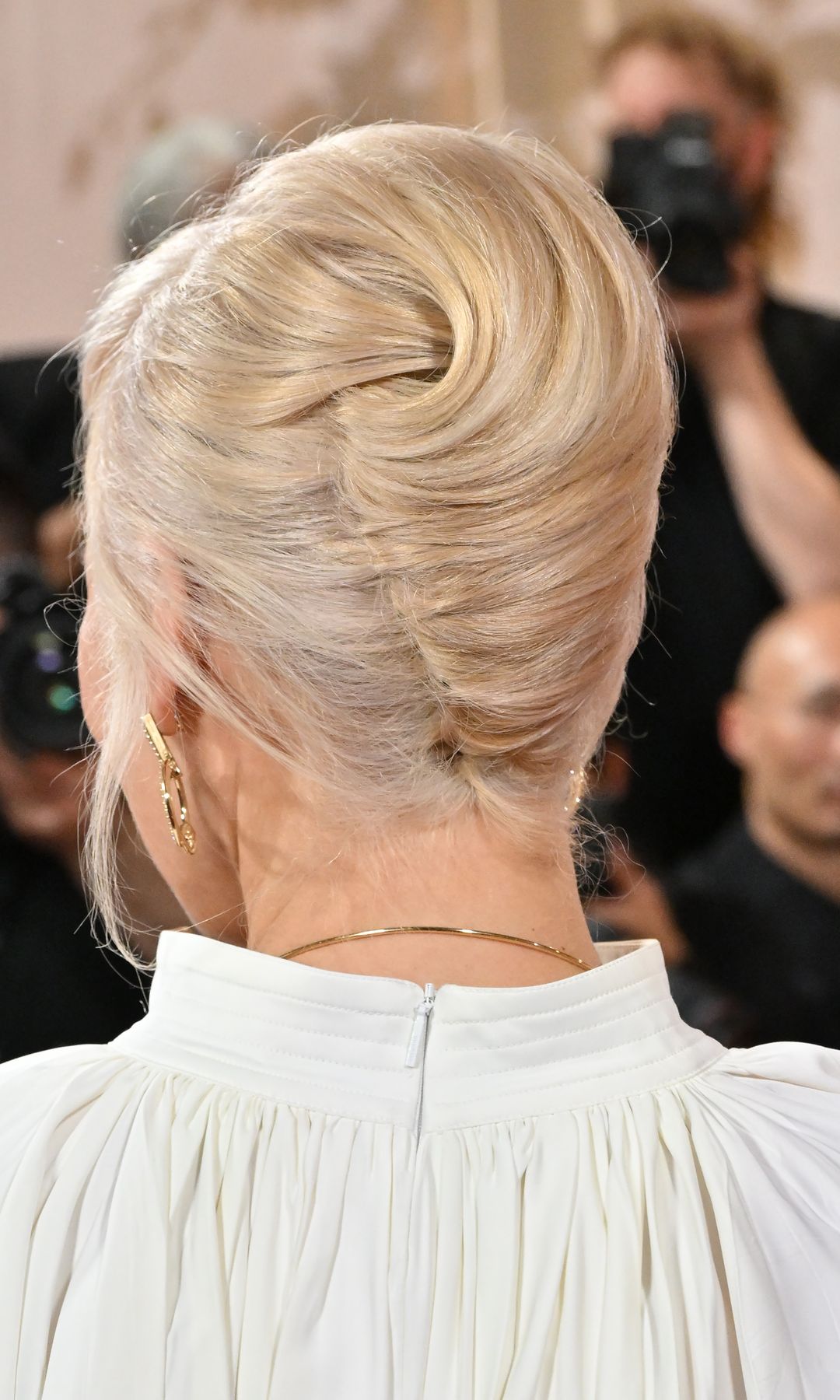 Recogido con volumen en coronilla y textura suave en rubio frío de Pamela Anderson