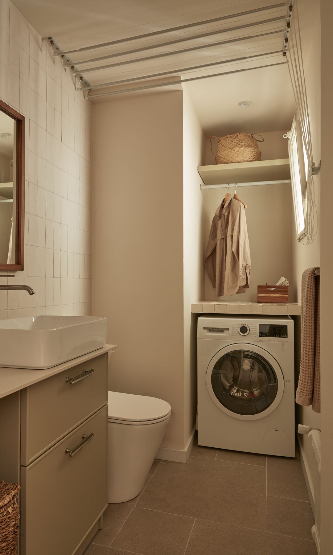 Lavadero en el baño con lavadora, barra para la ropa, estanterías y cestos