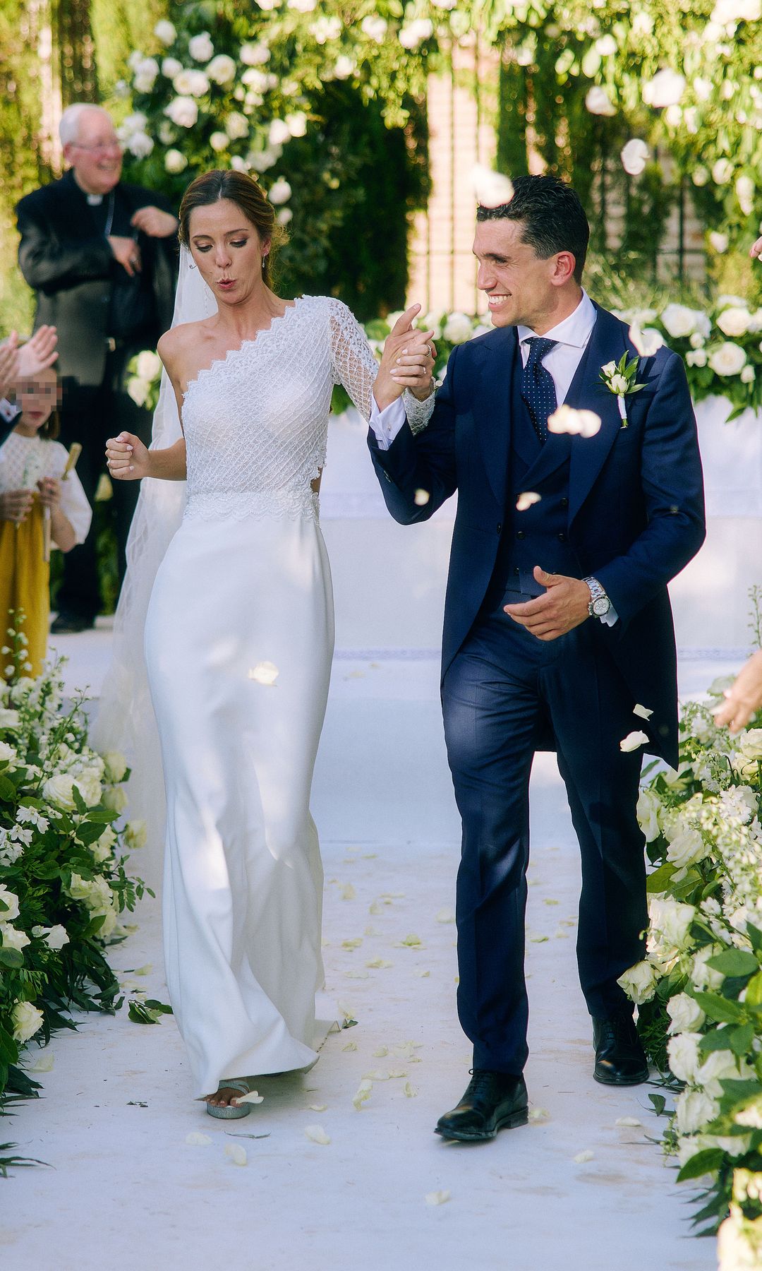 Fotografía de los novios, que caminan entre pétalos de rosas