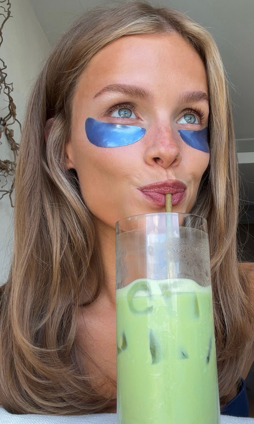 Josefine Vogt bebiendo un matcha con parches de ojos azules y el pelo suelto