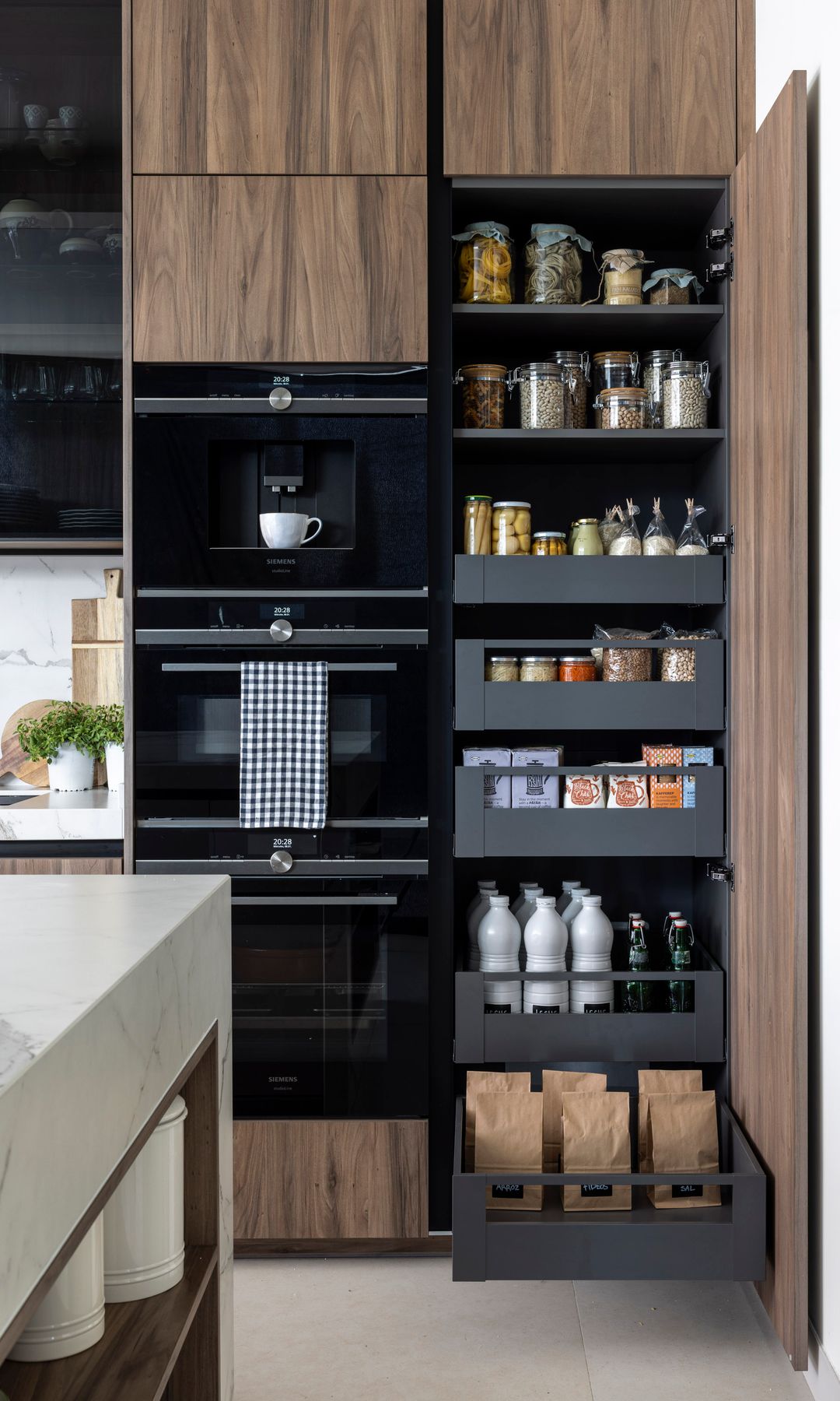 Cocina de madera con armario con gavetas extrapoles, horno, cafetera y microondas negros en columna 
