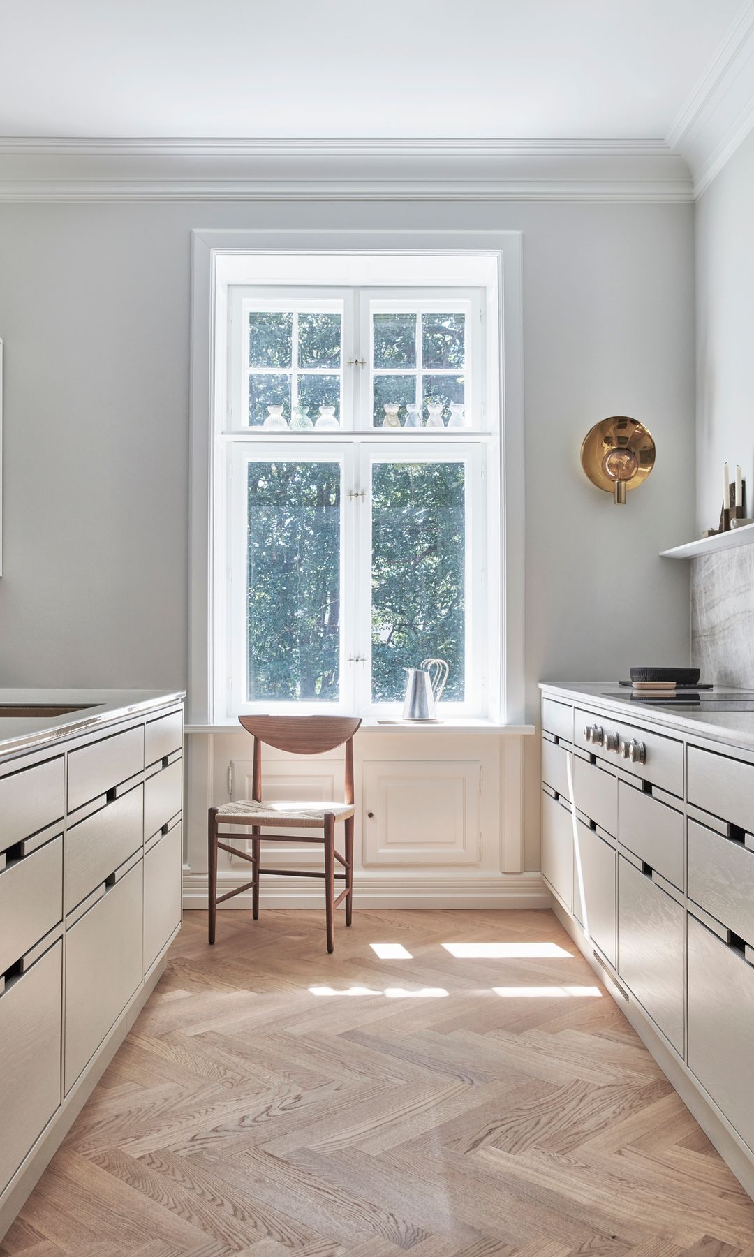 Cocina blanca con mucha luz, suelo de madera, silla de madera, ventanal blanco