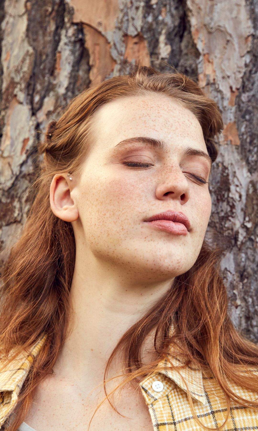 Mujer respirando apoyada en un árbol