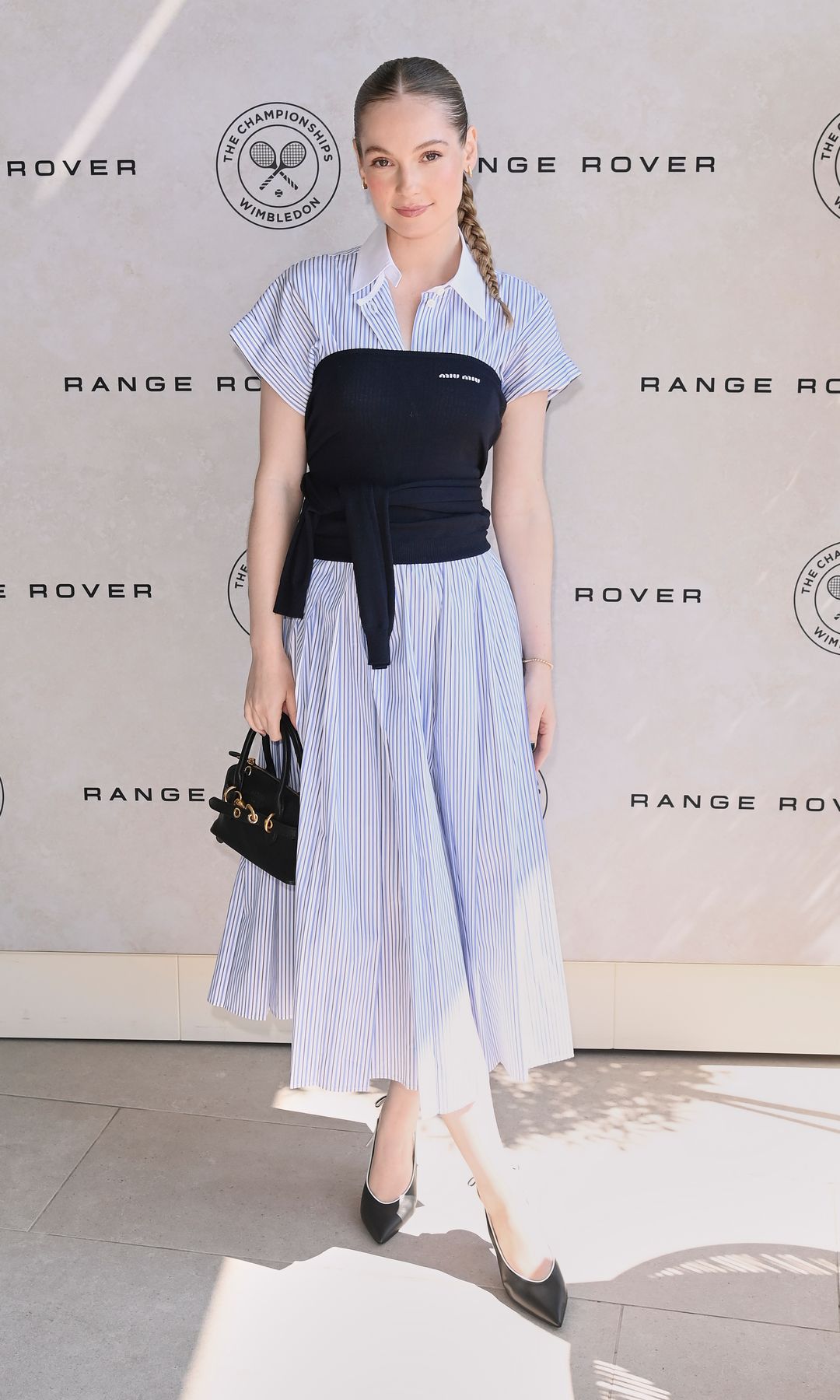 Hannah Dodd, actriz de 'Los Bridgerton' con un vestido camisero a rayas en color azul, un corpiño en color negro y accesorios en el mismo tono, en Wimbledon 2025  