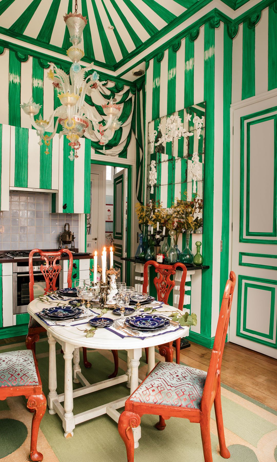 La colorida cocina de la casa con una carpa trampantojo, alfombra de Casa López, sillas Chippendale y candelabro de Murano.