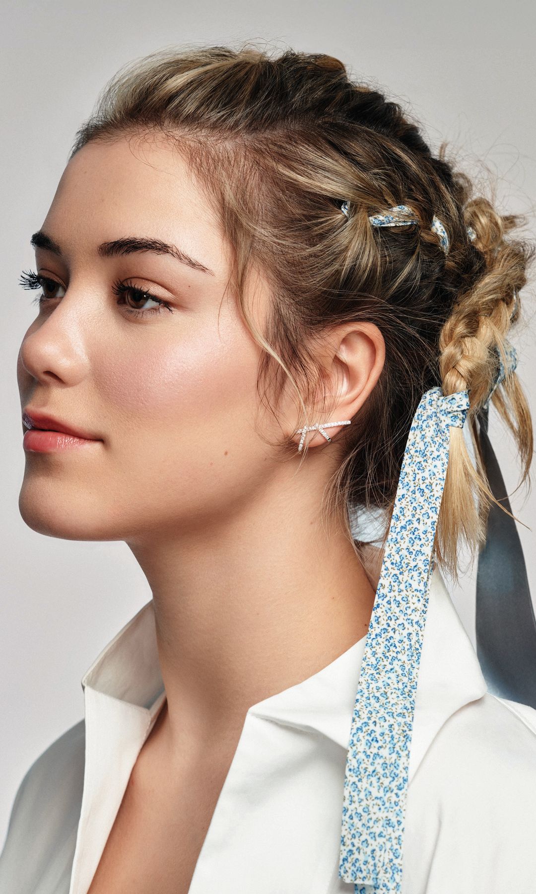 Aquí con un recogido de tres trenzas, una a cada lado y otra central, adornadas con lazo azul. “Para dotar de un efecto natural pero controlado al peinado, es importante mantener a raya los baby hairs. Para ello, aplica en húmedo unas gotas de aceite; aportarán suavidad y control”