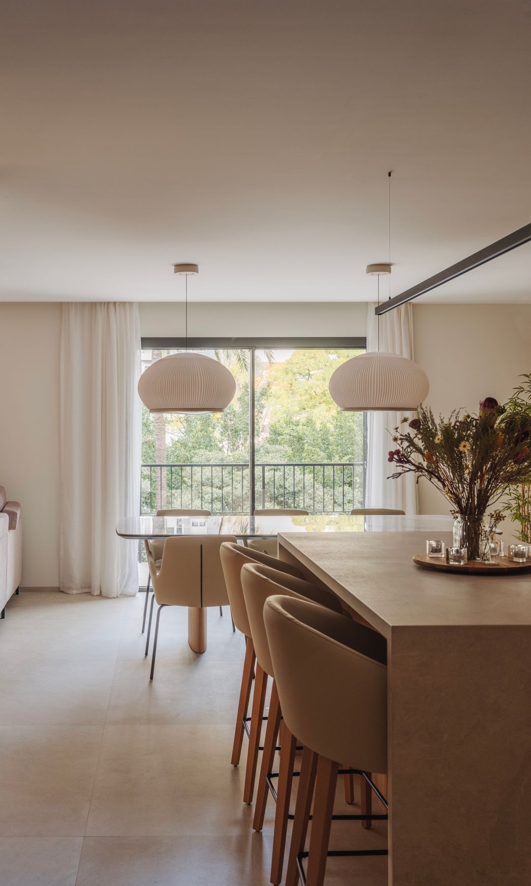Isla de cocina con taburetes altos, abierta al comedor con lámparas de techo