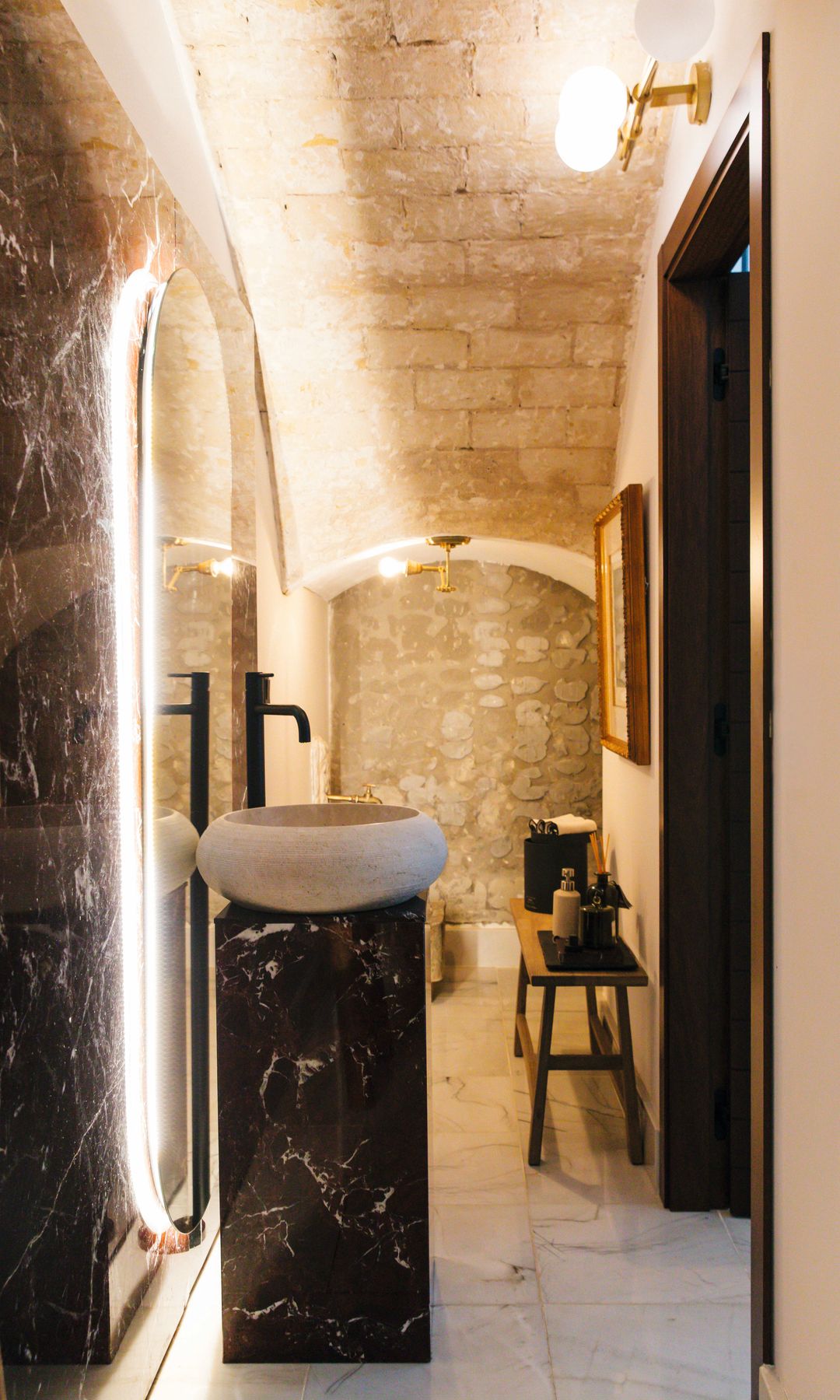 El cuarto de baño, lejos de lo convencional, se eleva como una pieza de diseño arquitectónico donde la materia cobra todo el protagonismo: elementos de Arance, piezas artesanales de Katatori y superficies de cuarzo configuran un espacio de gran fuerza estética