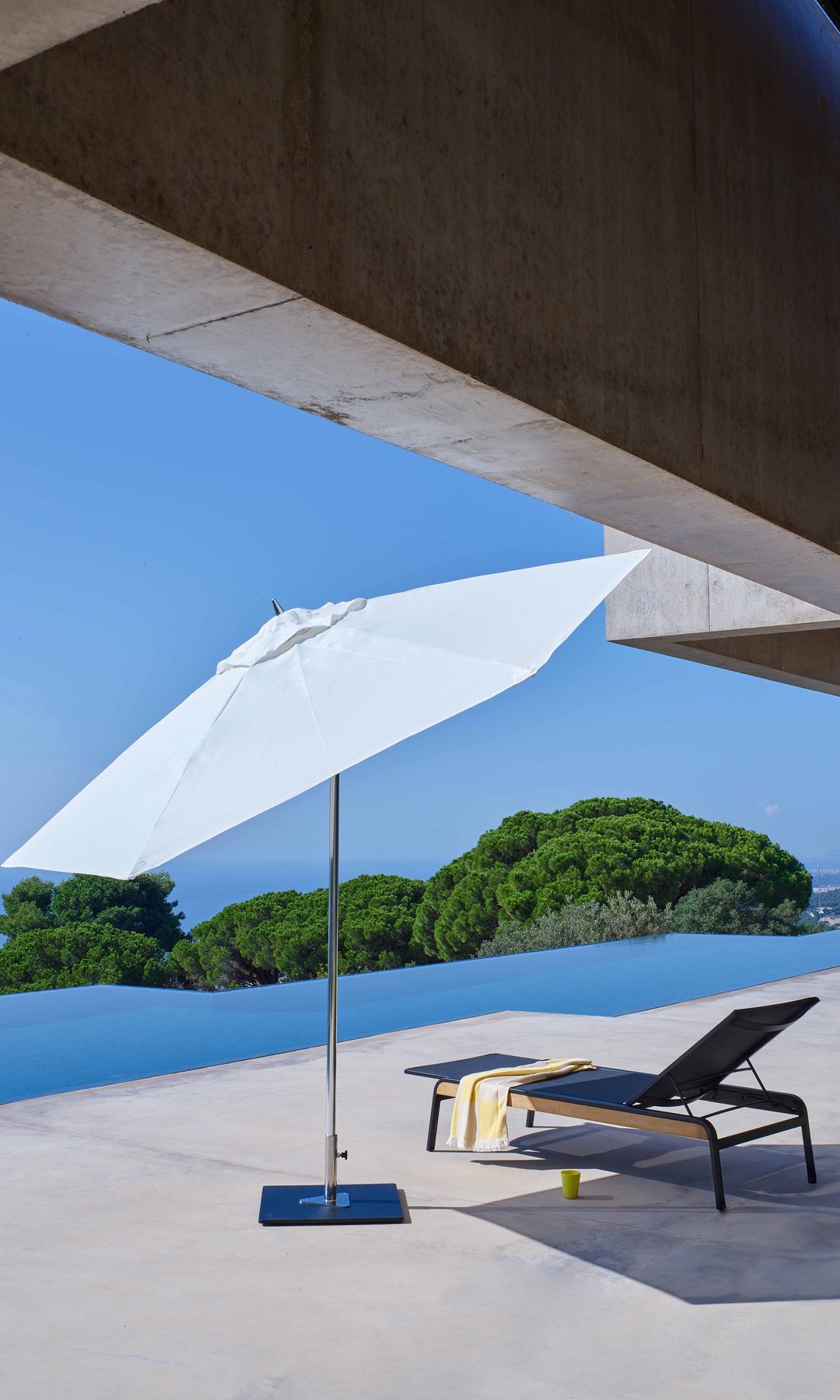 Piscina con sombrilla blanca y tumbona 