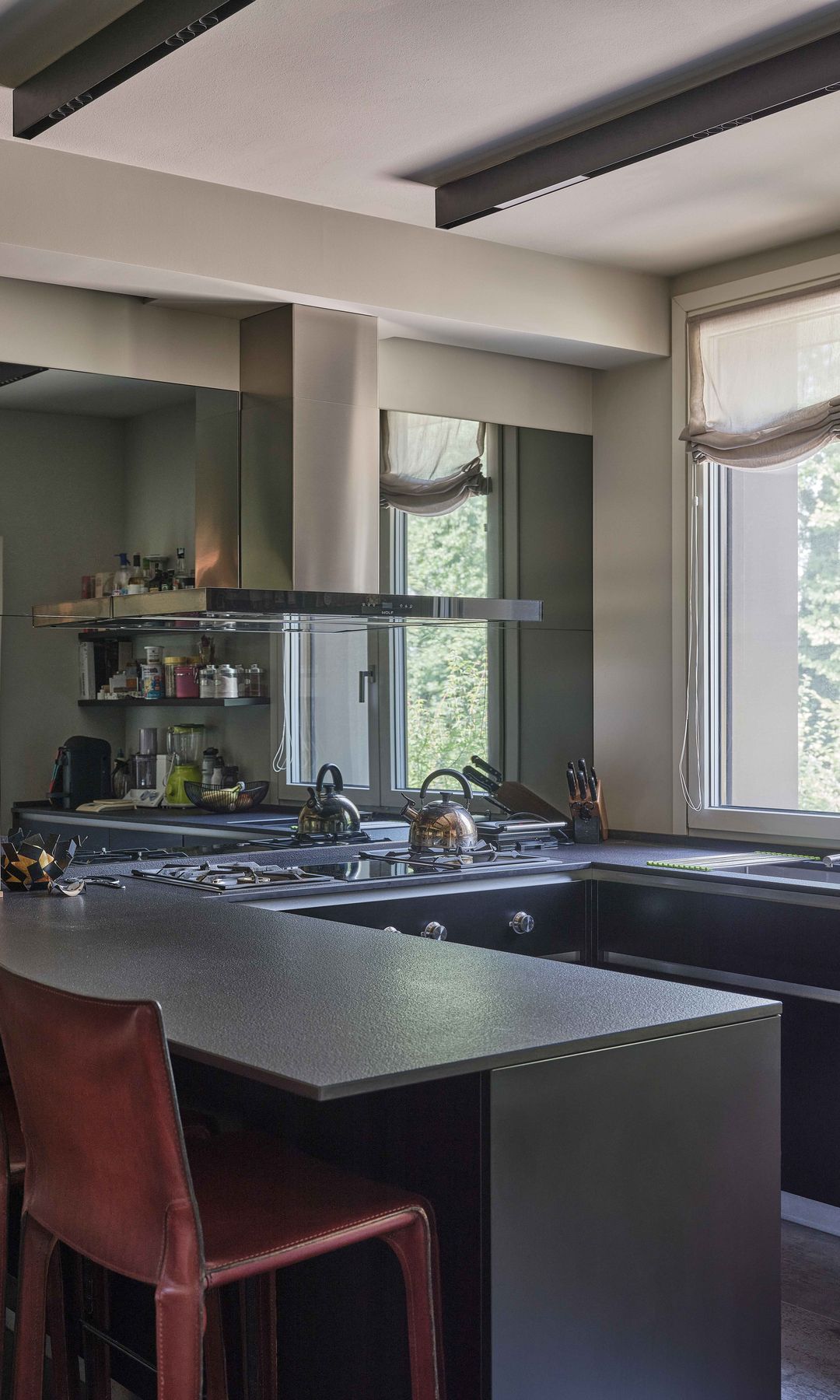 Cocina gris en U, vigas en el techo y barra con taburetes 