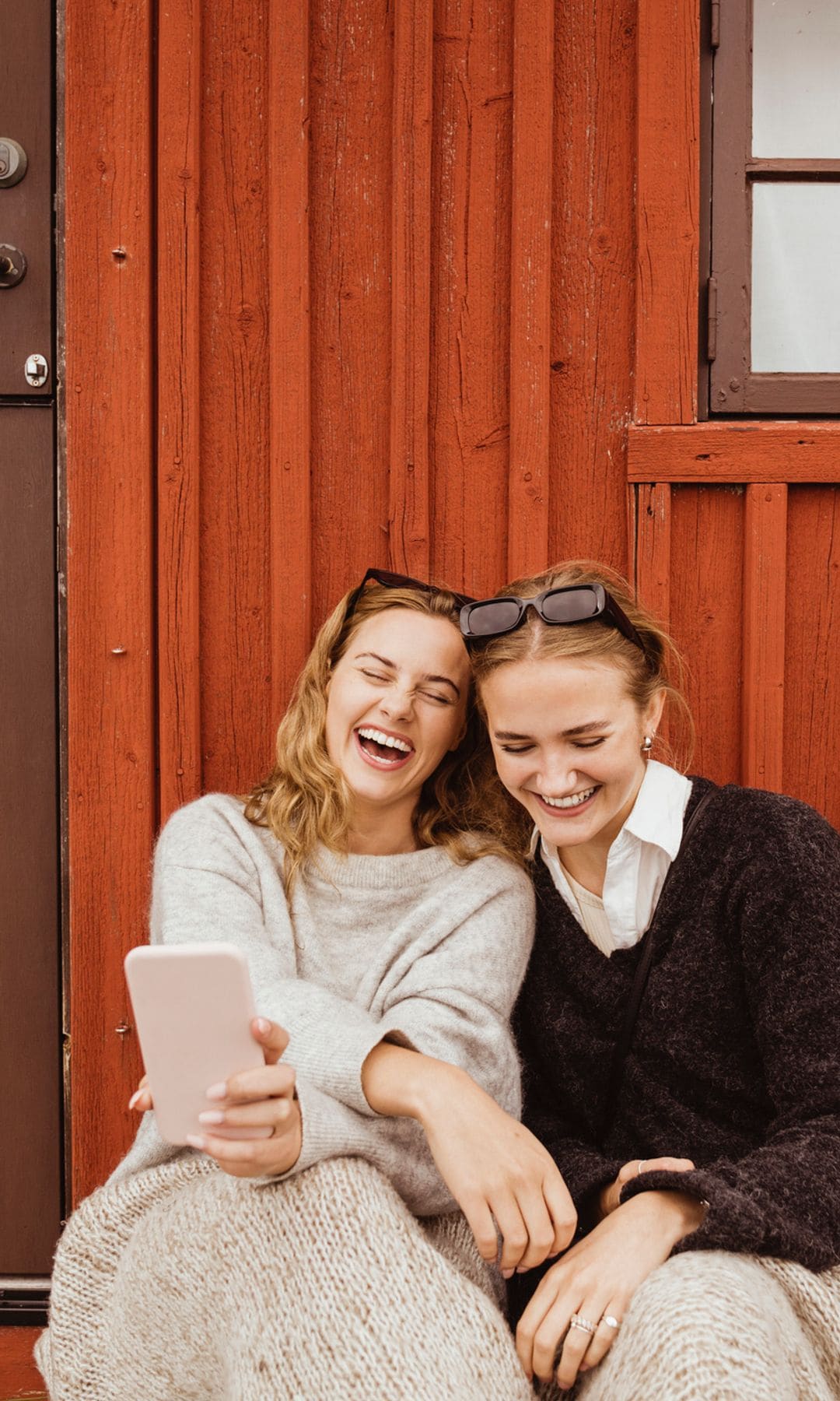 dos amigas riéndose mientras miran el teléfono móvil