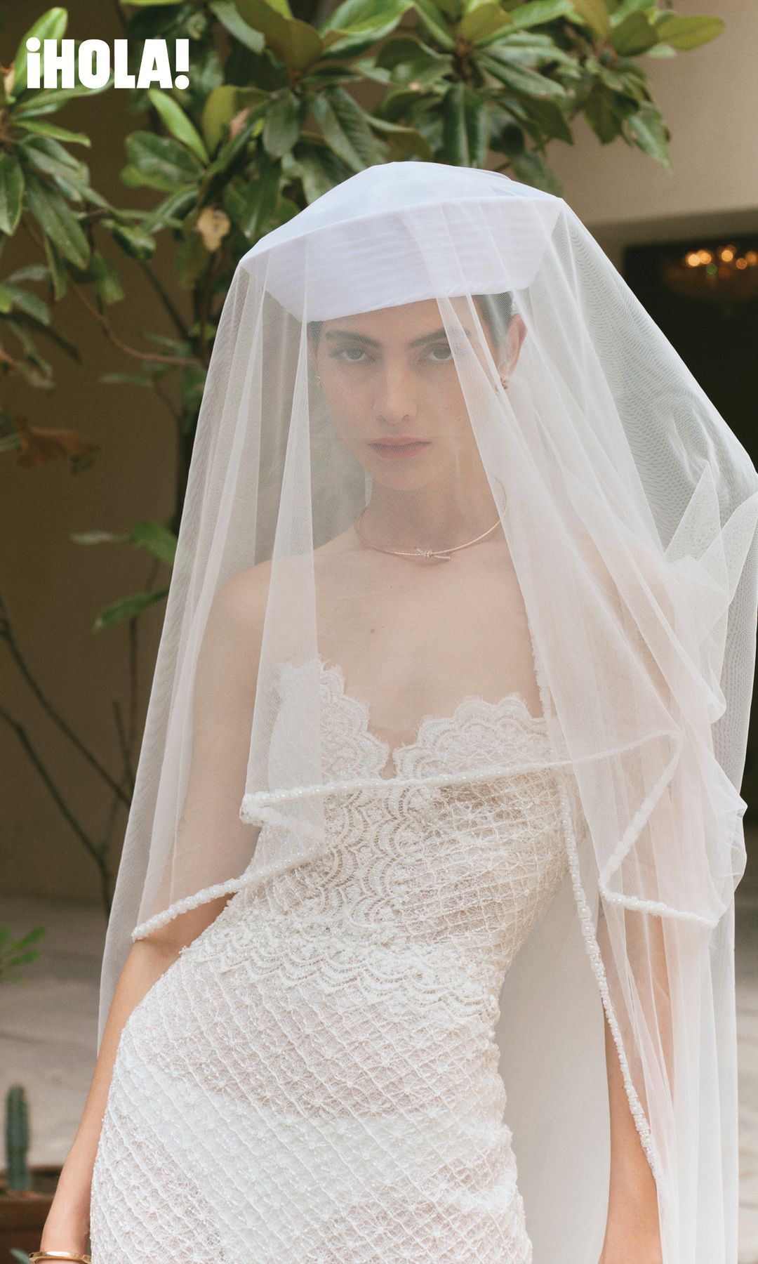 En esta imagen, la novia luce un vestido ceñido al cuerpo y un velo a juego de Rosa Clará, acompañado por un collar Knot en oro rosa con diamantes, de Tiffany & Co. 