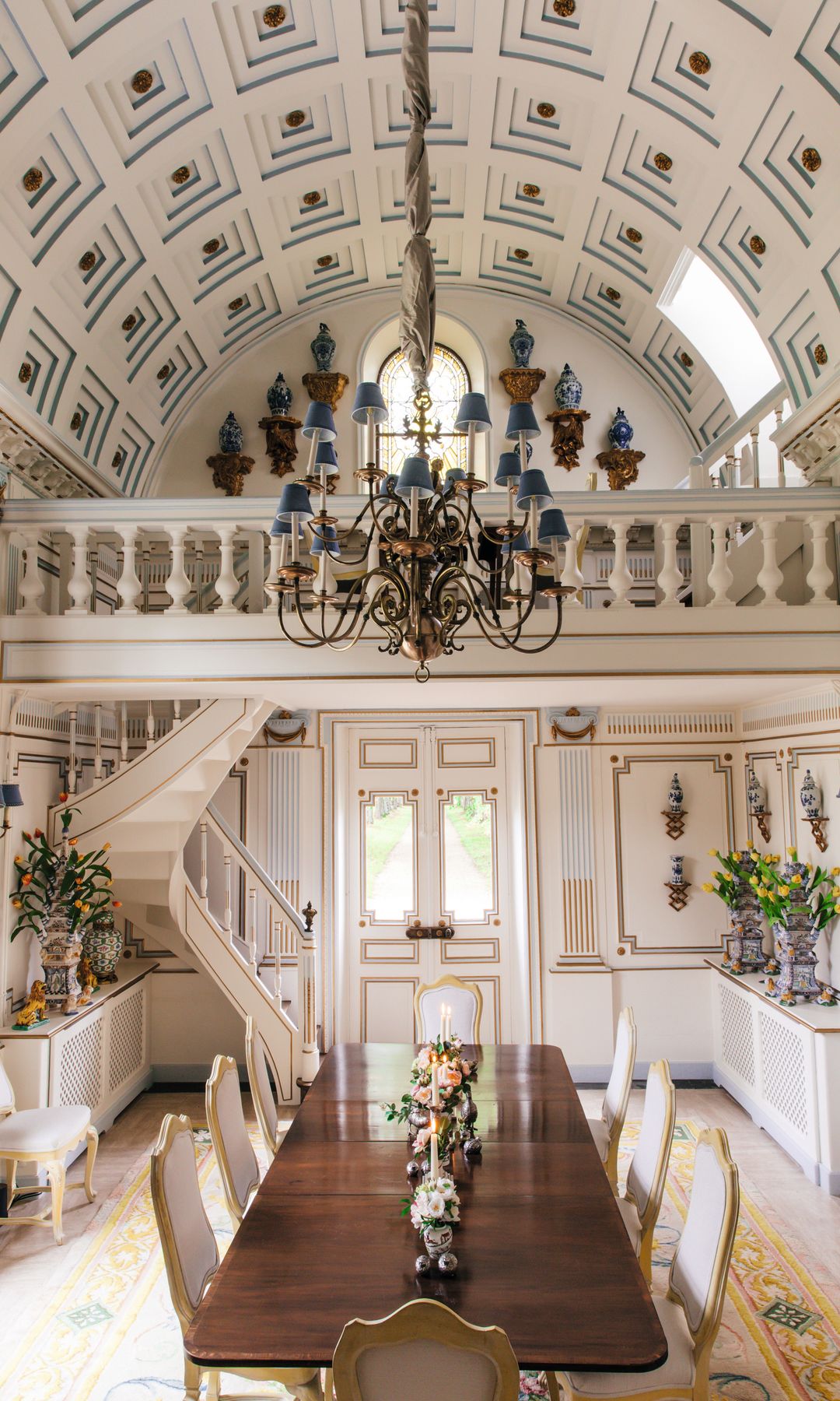 Comedor con mesa larga, sillas, candelabro y escalera