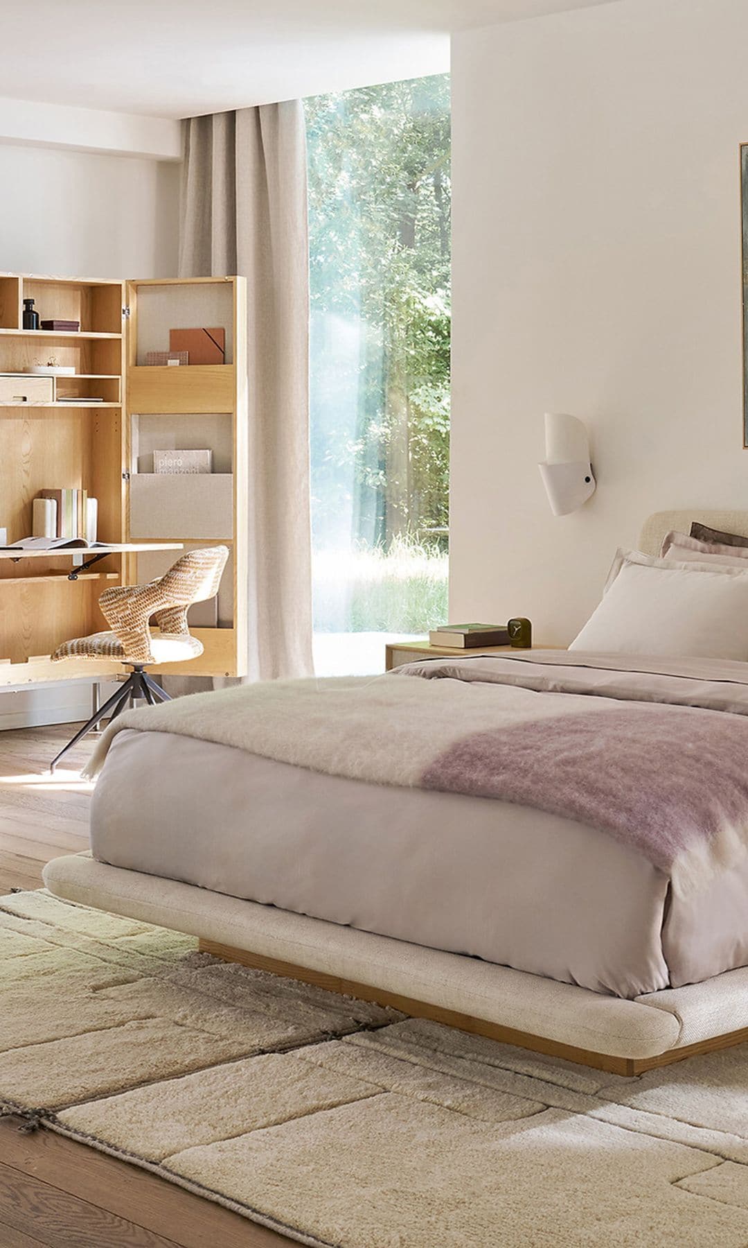 Dormitorio con cama tapizada, cuadros en la pared del cabecero, ropa de cama rosa, cojines, escritorio independiente 