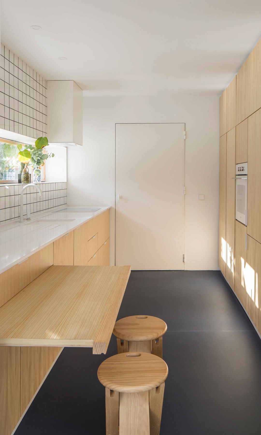 Cocina pequeña con muebles de madera hasta el techo, azulejos y barra de madera con. taburetes altos