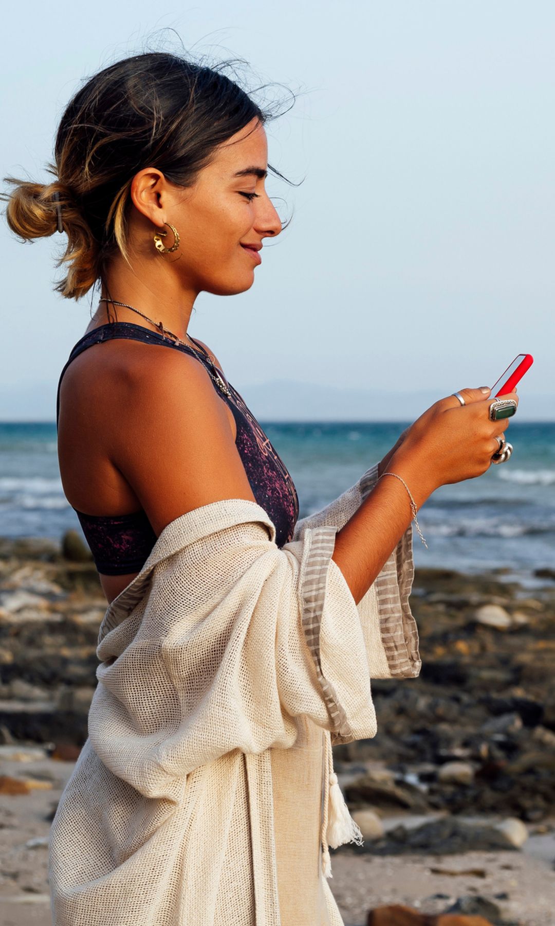 mujer sonriente usando el móvil en la playa