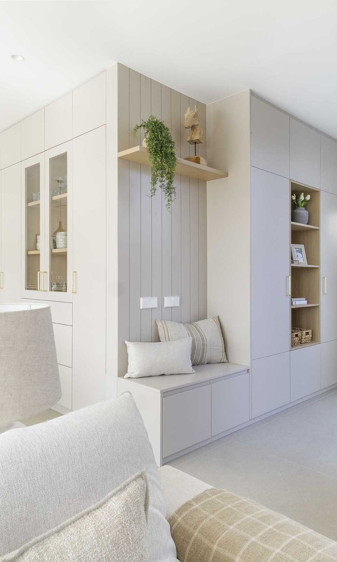 Recibidor abierto al salón con mueble a medida de color blanco a juego con el sofá y el suelo 