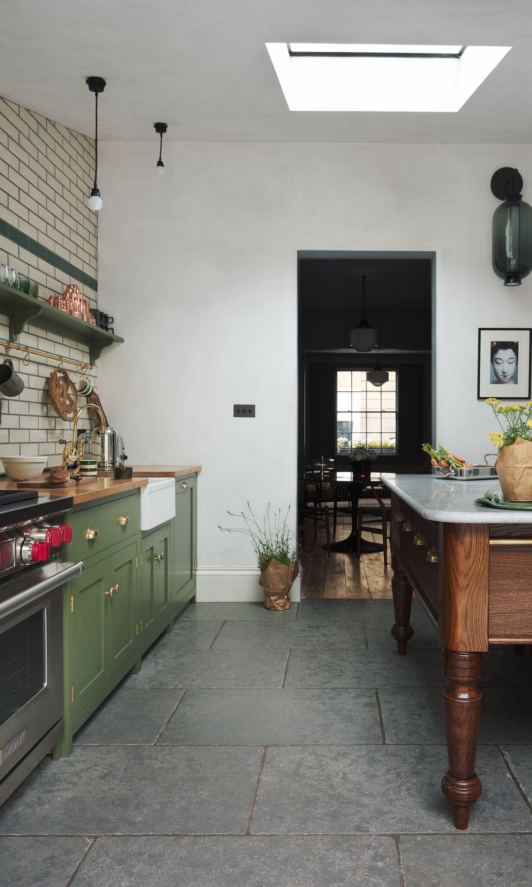 Cocina con mesa de madera antigua, azulejos en la pared, muebles verdes, claraboya en el techo, cocina de gas