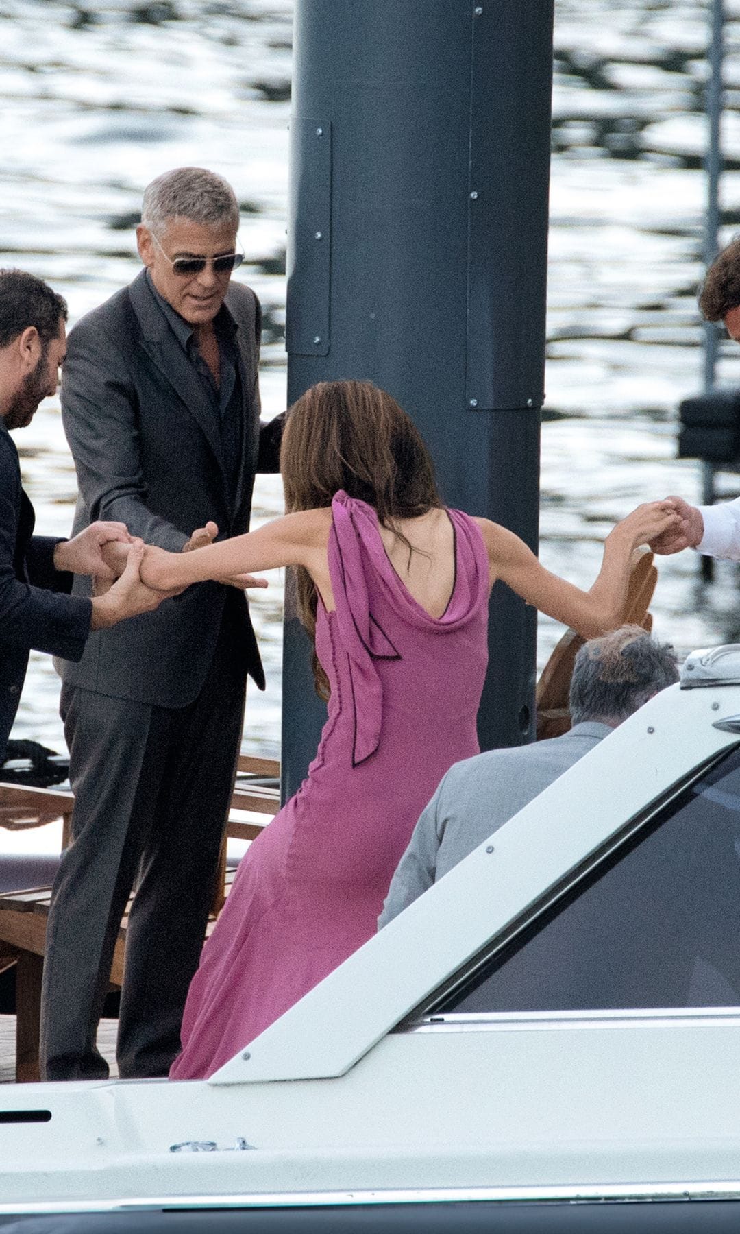 El actor, ayudando a Amal a subirse al barco que les llevaría hasta Villa Passalacqua, donde se celebró la cen