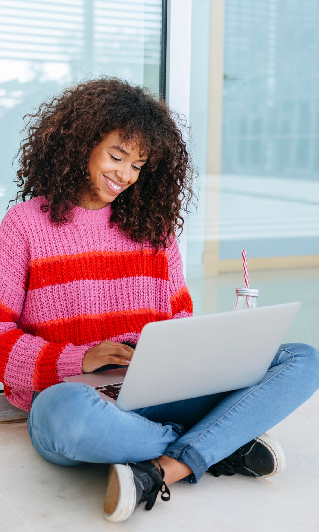 Mujer sentada en el suelo con un ordenador estudiando