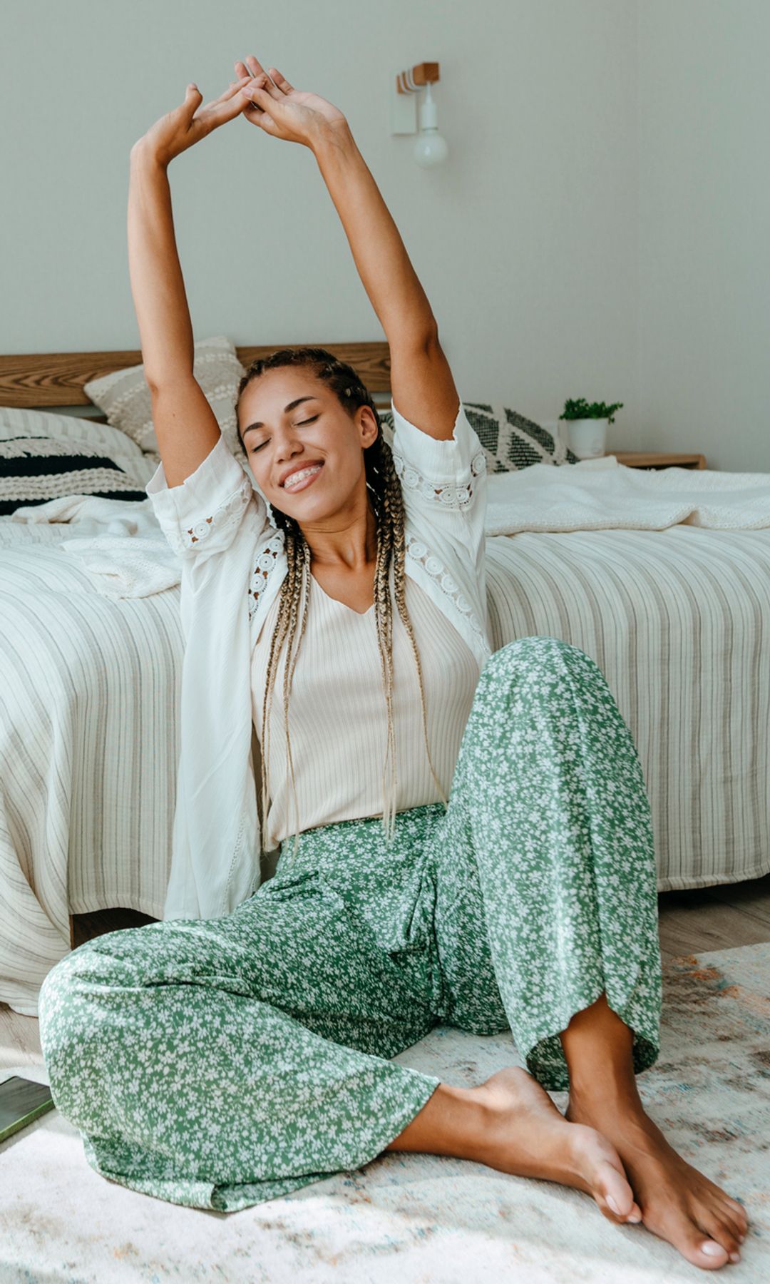 Mujer delante de la cama estirando y feliz