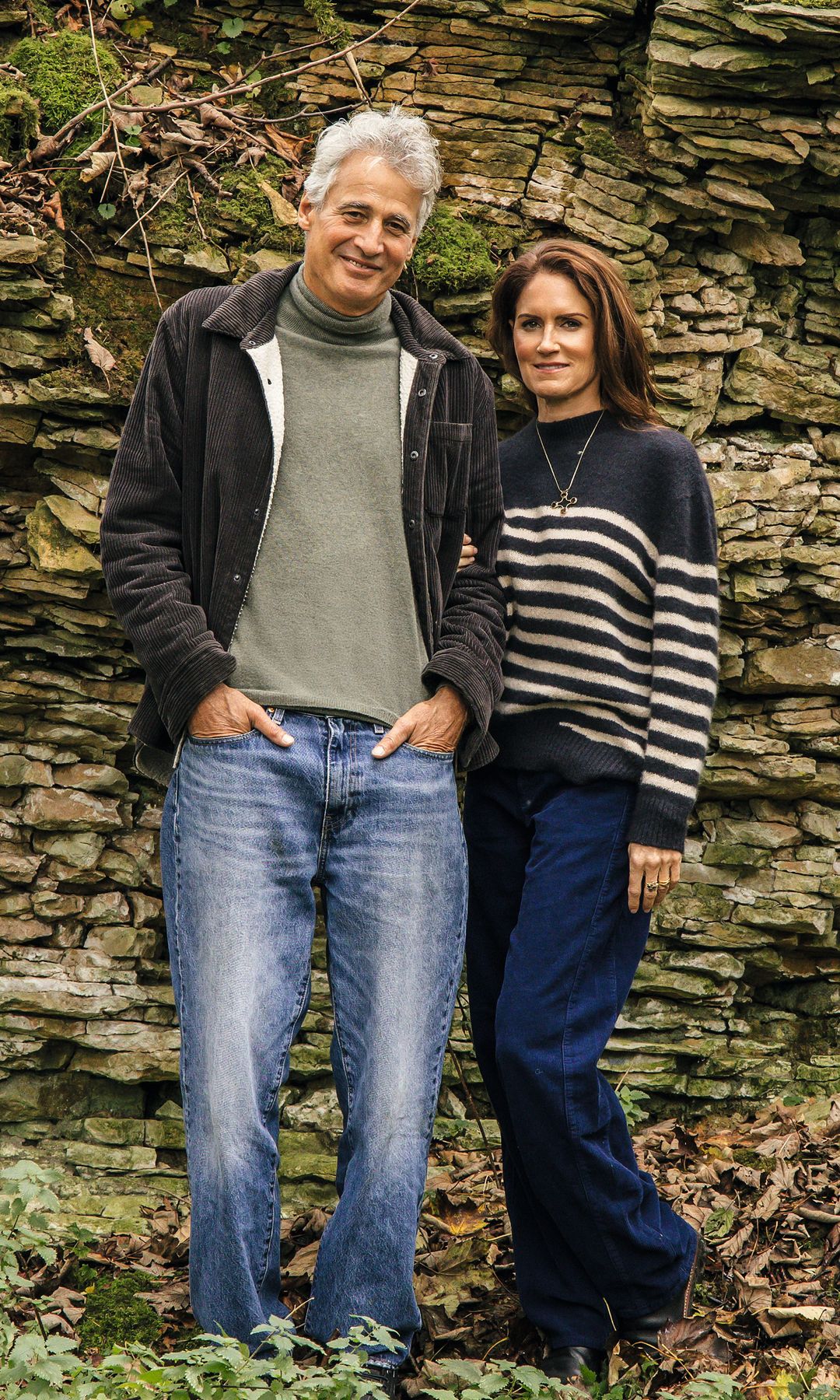 La pareja posa en los jardines de la casa en un fondo de piedras entre vegetación y naturaleza