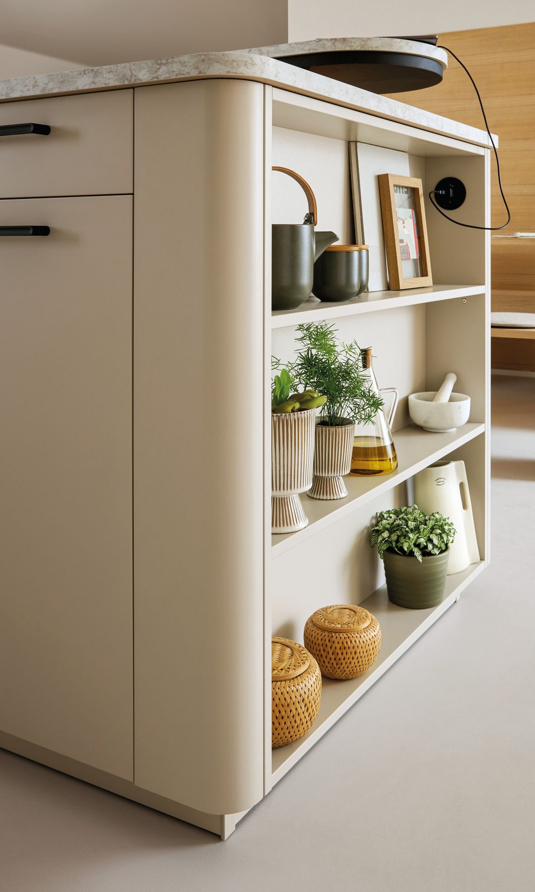 Isla de cocina con un lado abierto con baldas con plantas, objetos de adorno, enchufe, accesorios cocina