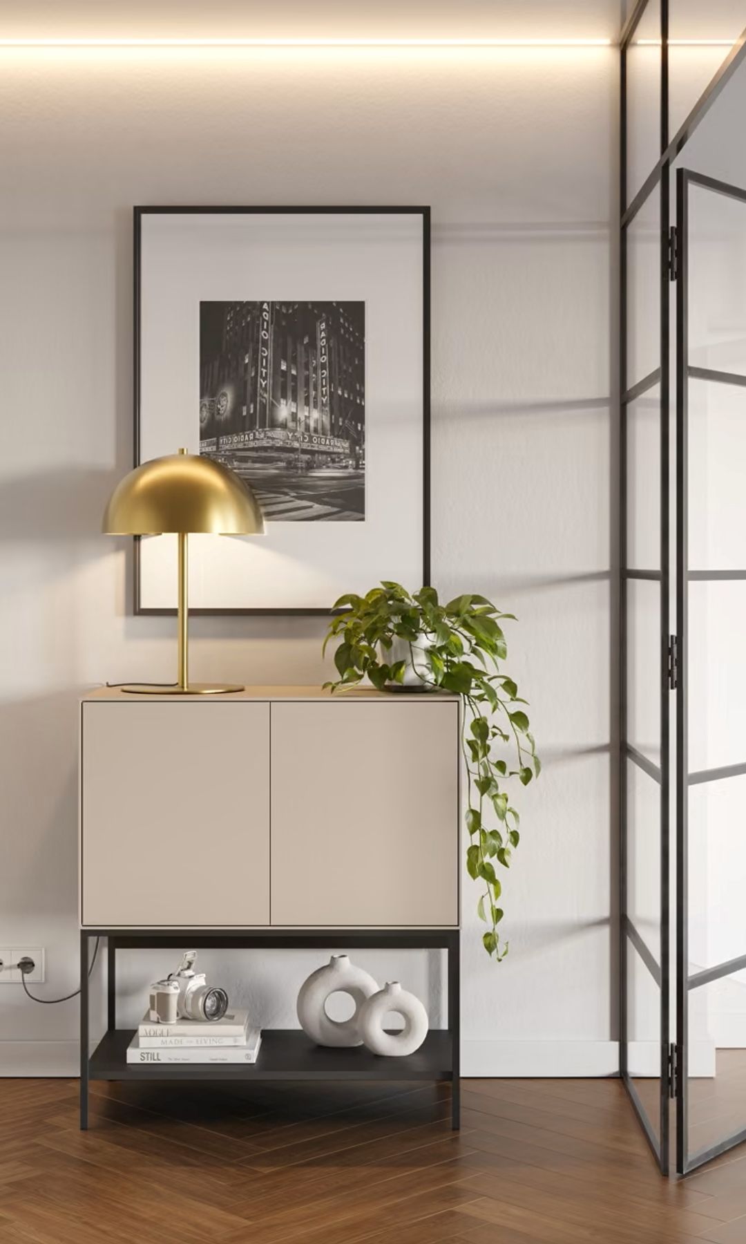 Recibidor con mueble con armario en la parte inferior y abierto en la inferior, lámpara de sobremesa dorada, cuadro en la pared, tabique de cristal 