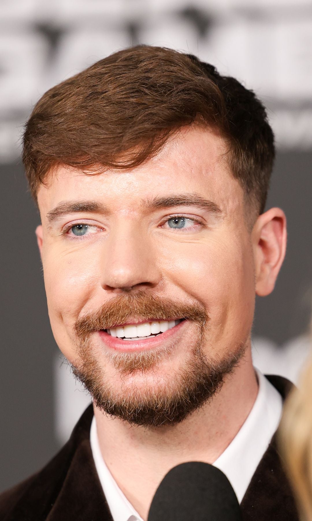MrBeast, con barba y bigote, sonríe mientras habla en un micrófono.