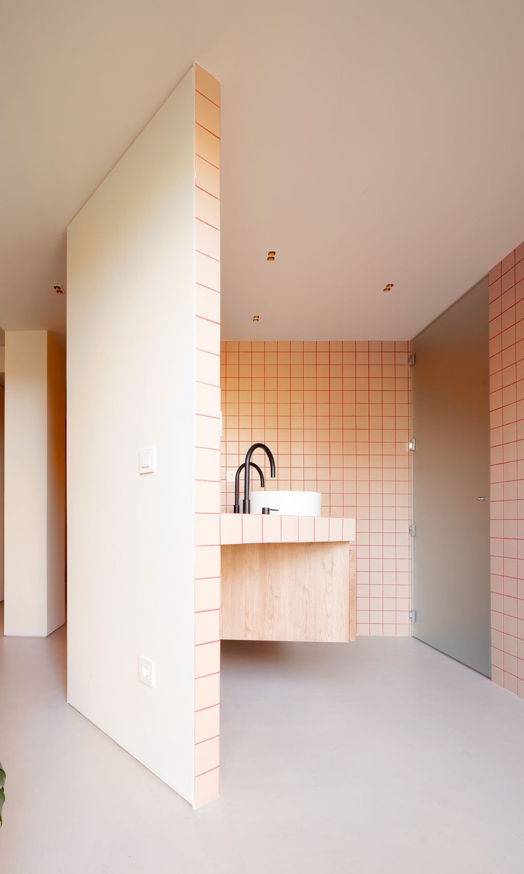 Baño revestido de azulejos blancos con las juntas rojas