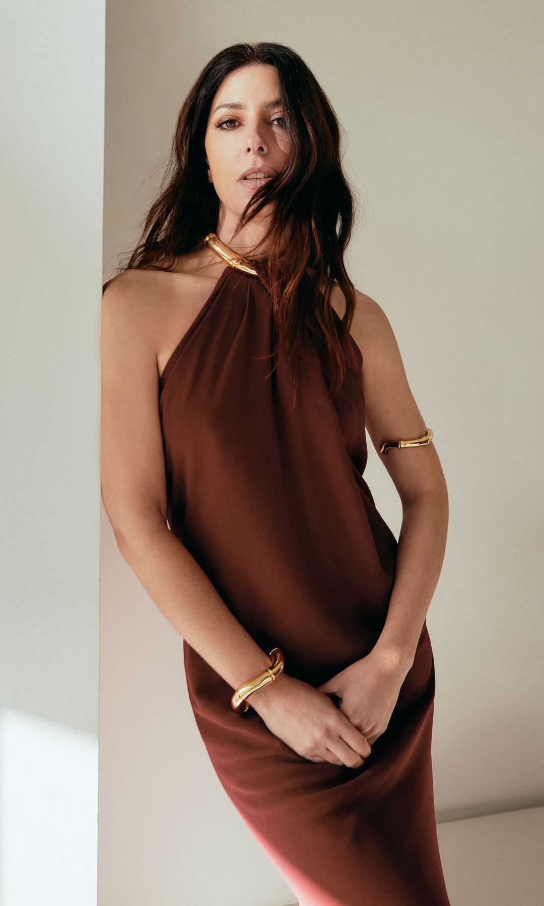 La protagonista con vestido de escote halter, y brazaletes dorados, de Gucci. 