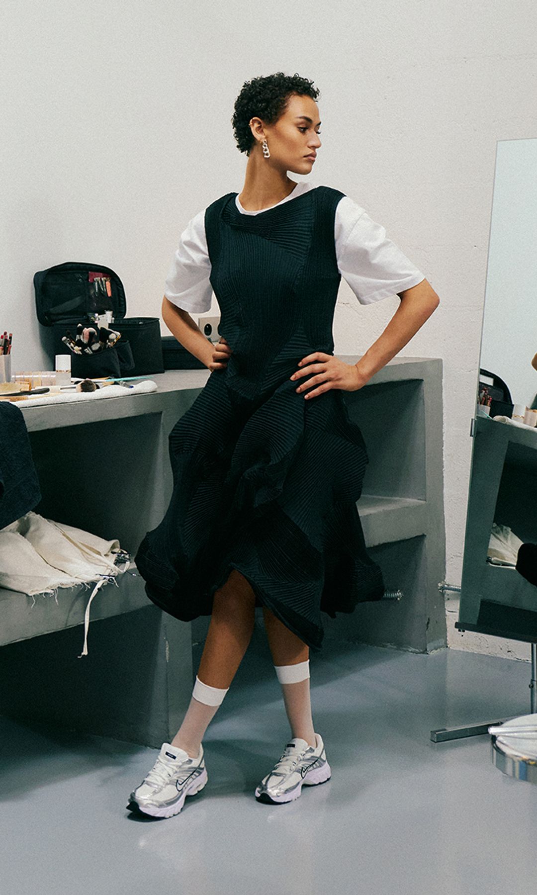 Mujer con pelo corto, vestido negro con camiseta blanca y zapatillas Nike Air Max Moto 2K