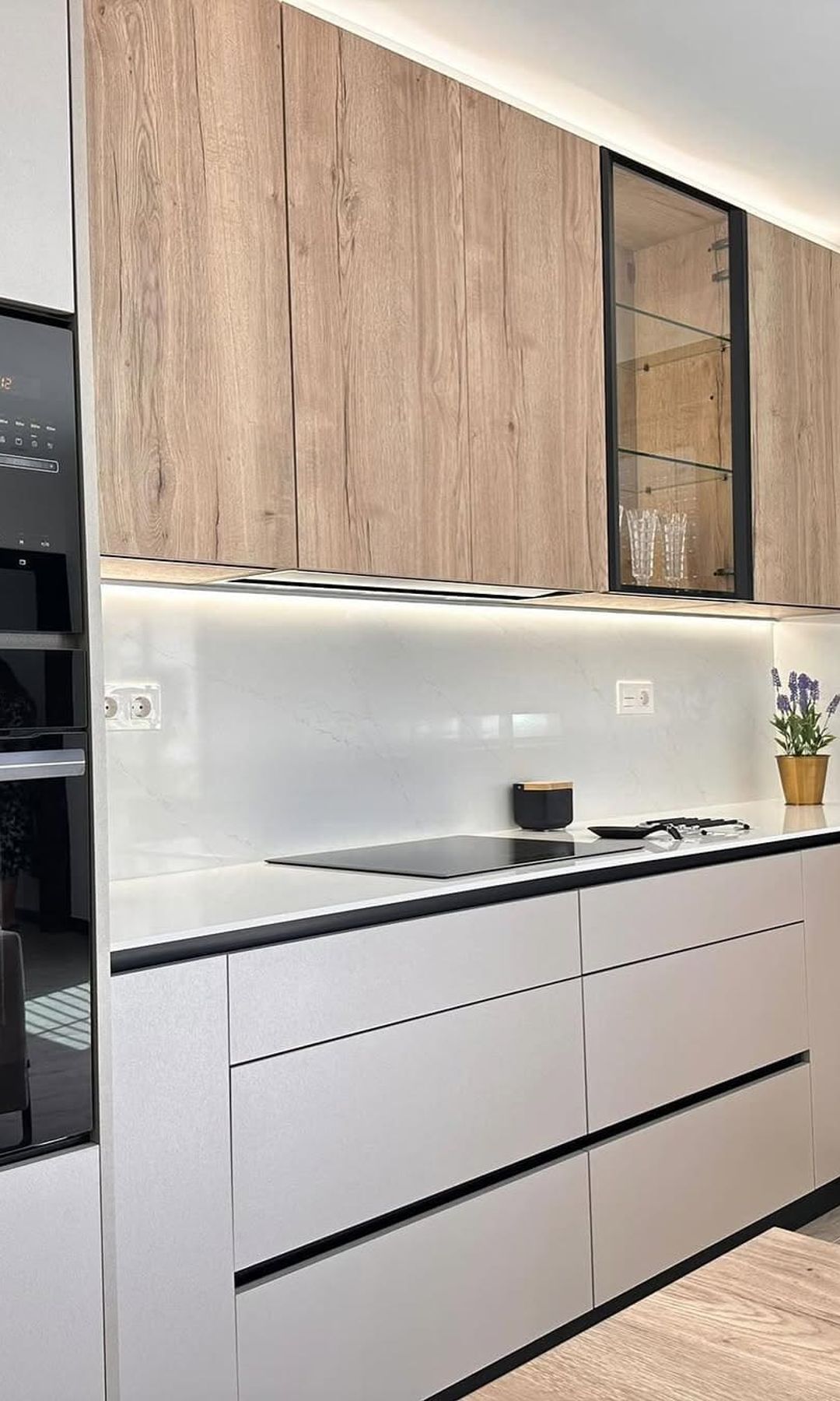 Cocina blanca y de madera, con armarios hasta el techo y módulo superior de vitrina