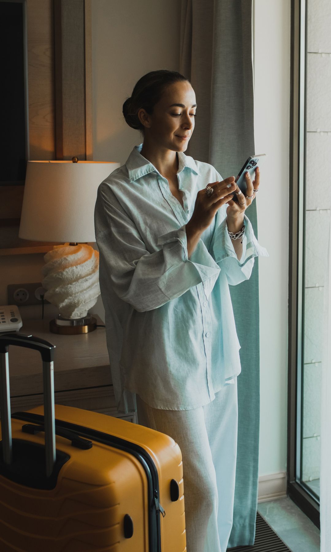 Mujer con una maleta en un hotel hablando por teléfono