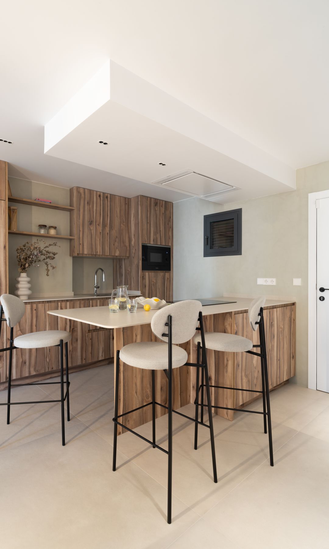 Cocina con isla, muebles de madera y taburetes altos 