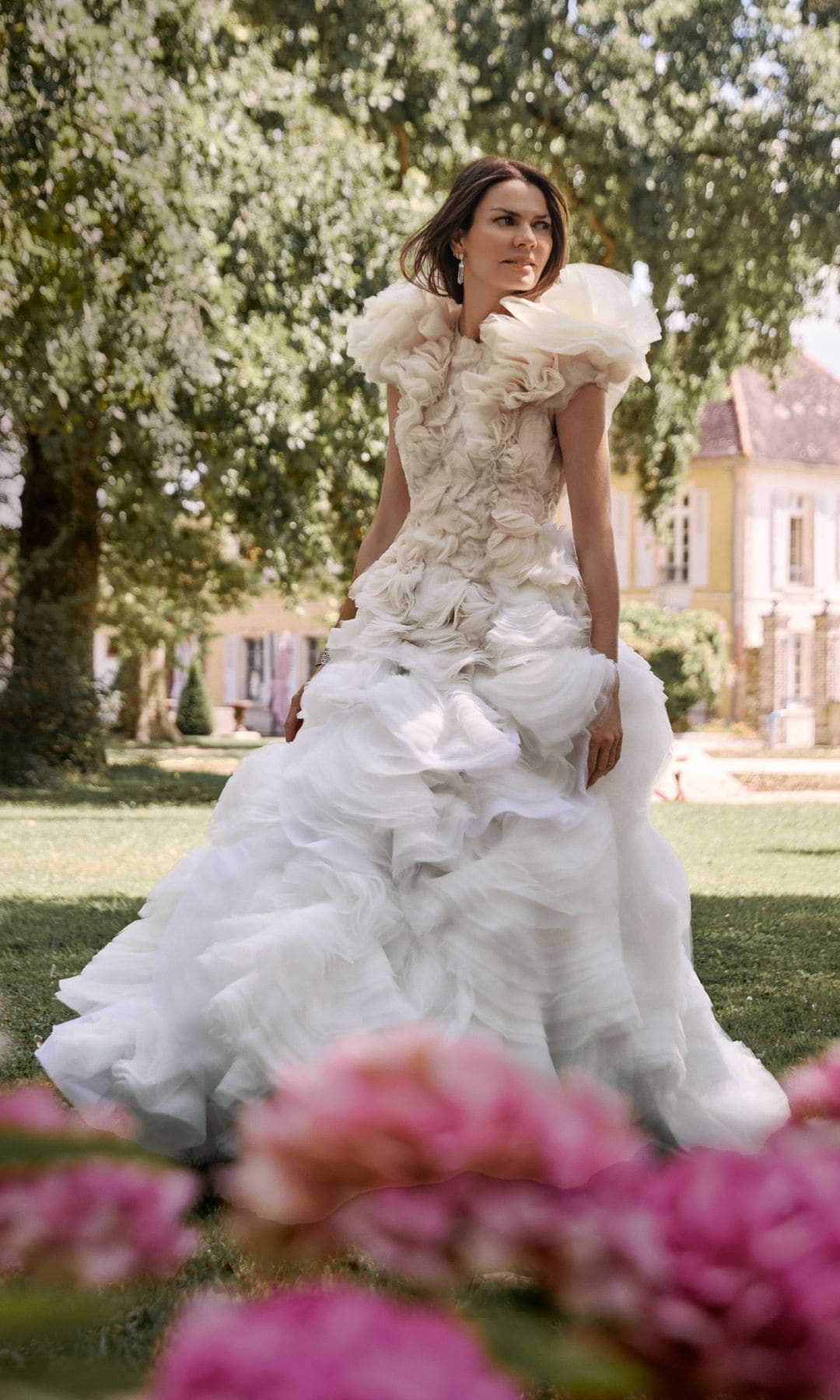 En un rincón del jardín, Alejandra de Rojas posa con vestido de organza y tul de seda, en color marfil, cuyo protagonismo recae en el corpiño y los hombros, recamados de flores en relieve. Es una propuesta  de Jan Taminiau. Las joyas son de Suarez