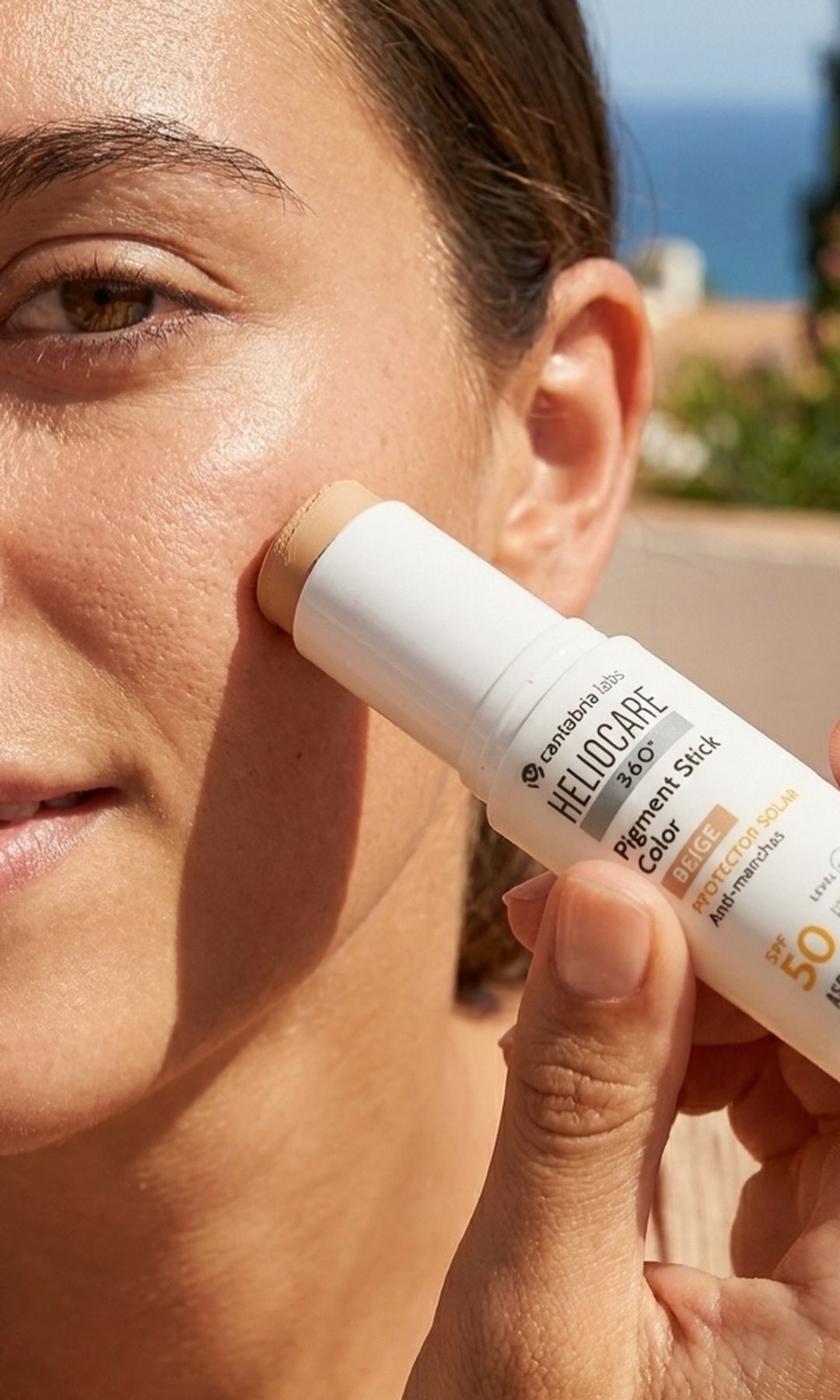 Mujer reaplicando protector solar en stick SPF 50 sobre el rostro durante un día soleado.