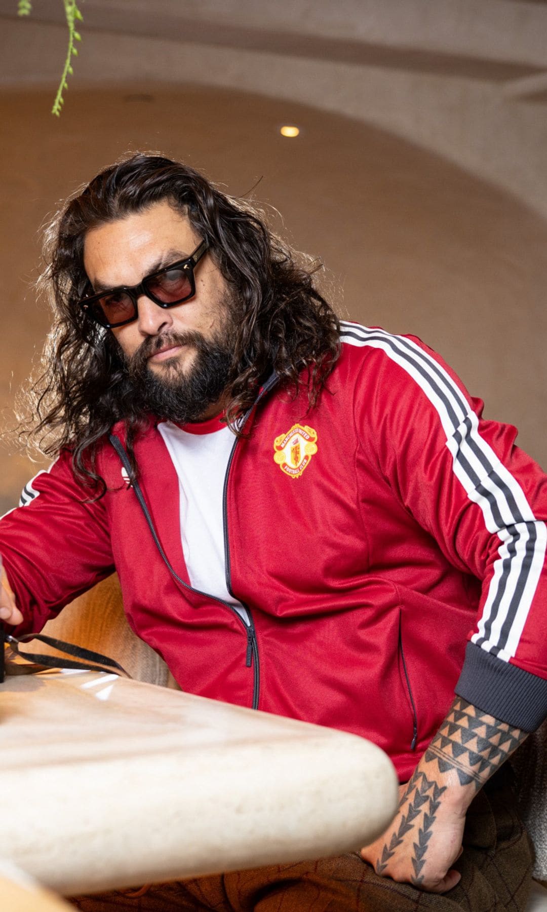 Jason Momoa en un restaurante, con chaqueta roja y gafas