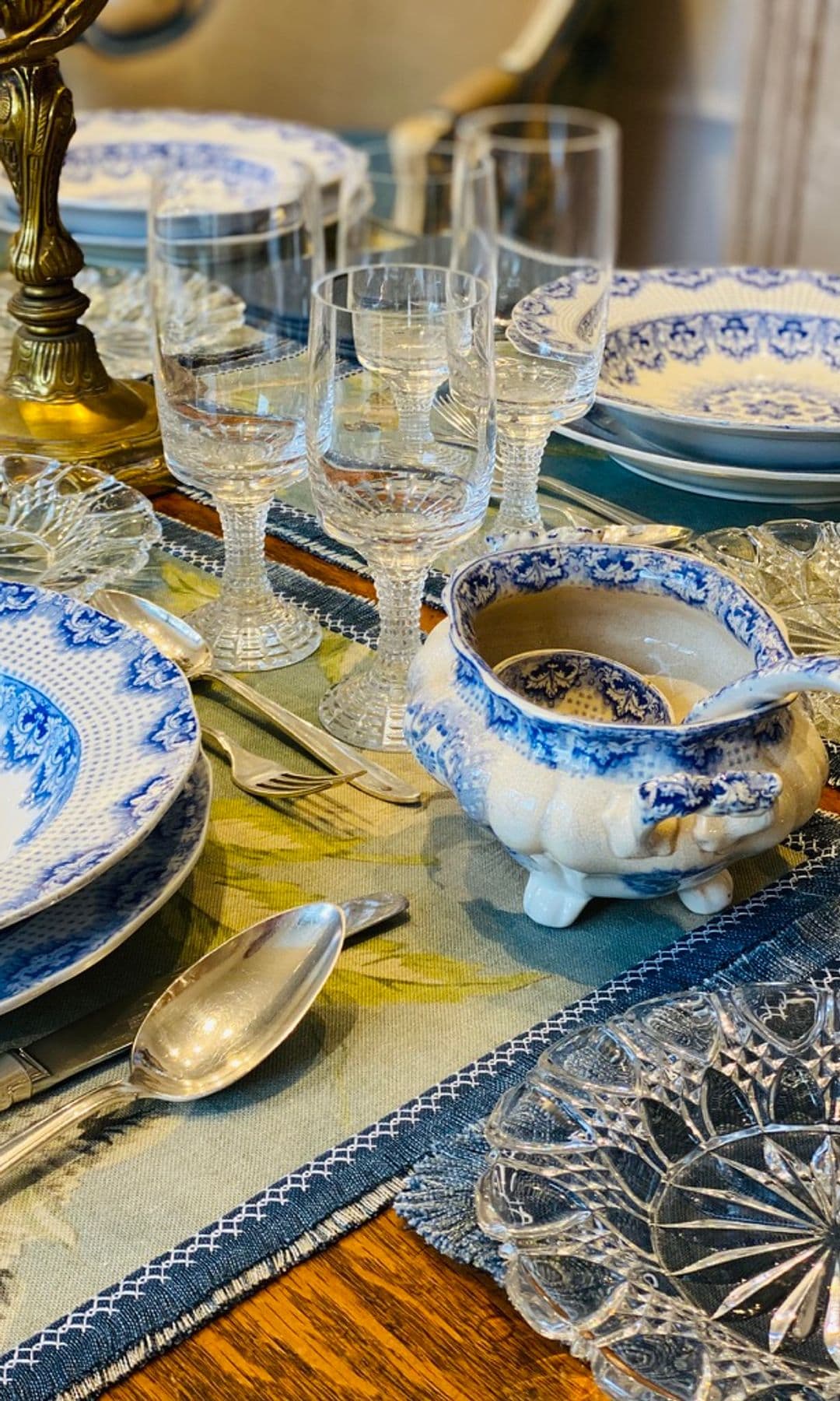 Mesa de Navidad en tonos azules con mantel, vajilla azules, salsera, copas, candelabro de bronce