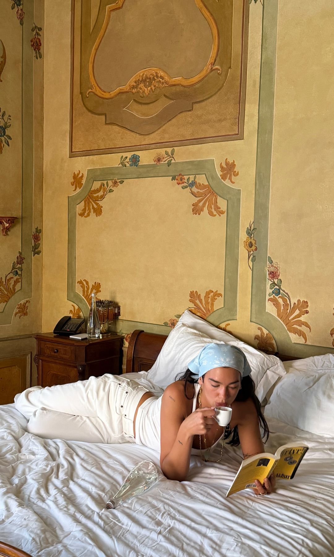 Dua Lipa tumbada en la cama con un café leyendo un libro