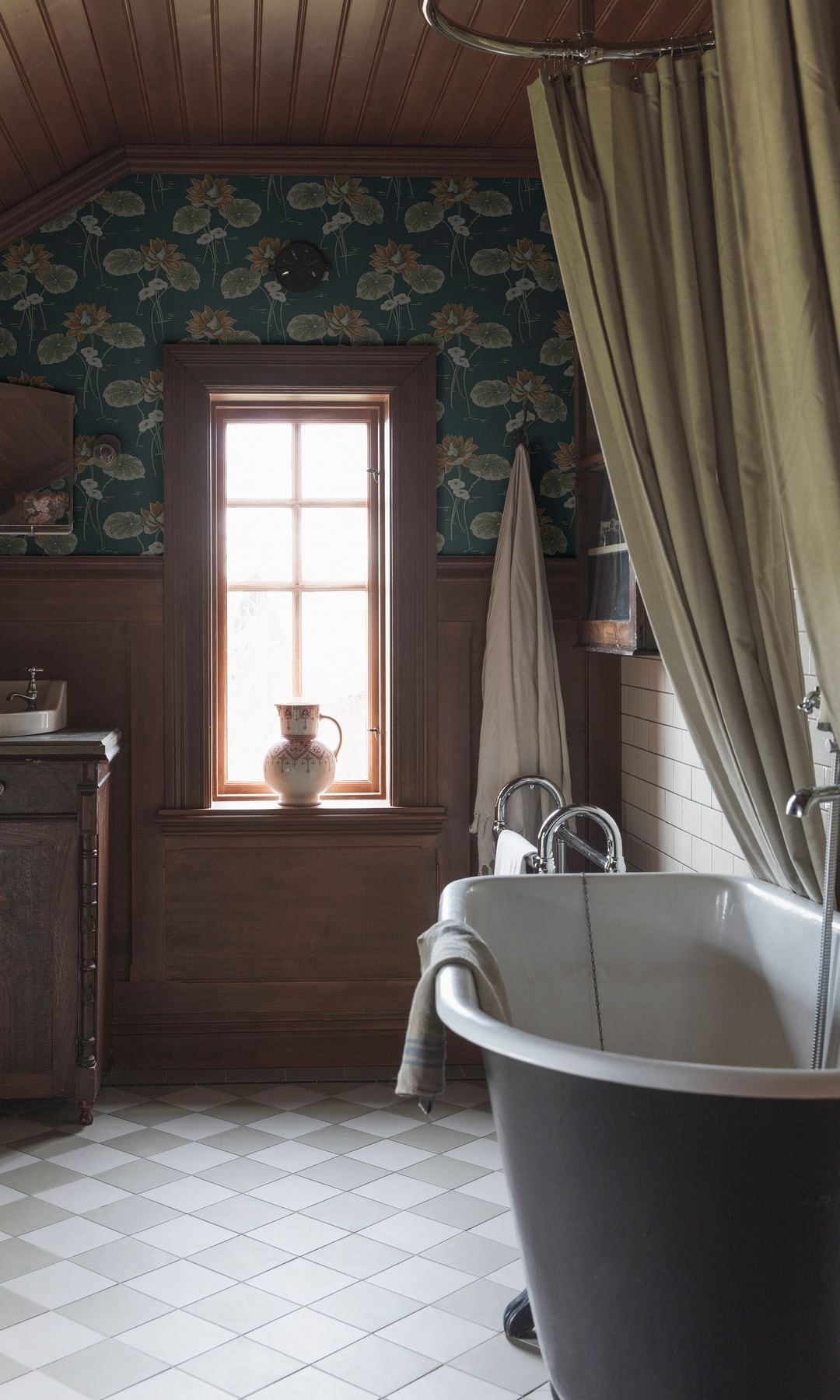 Baño con bañera exenta antigua, suelo porcelánico, techo de madera, papel pintado