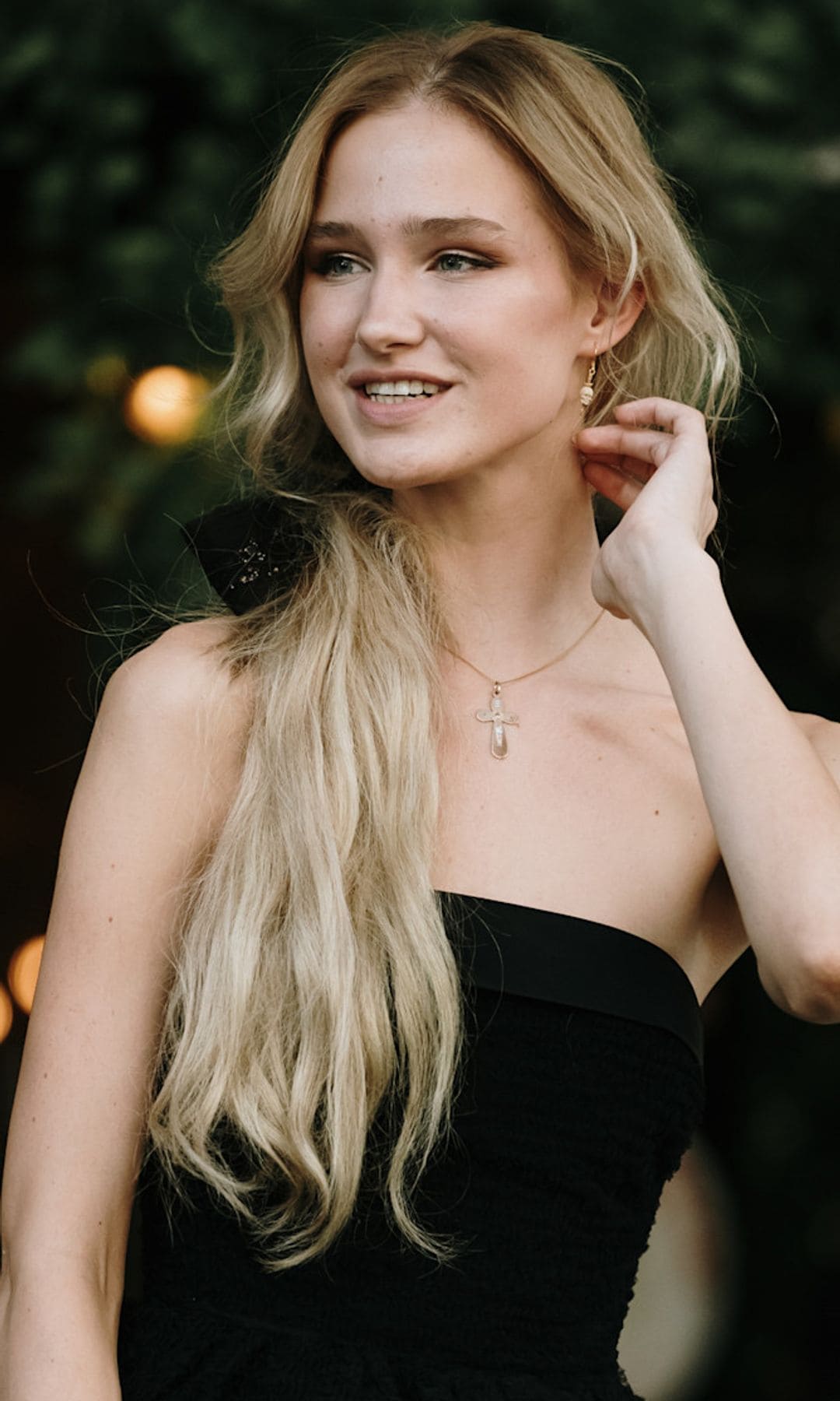 Invitada con vestido negro palabra de honor y coleta rubia con lazo
