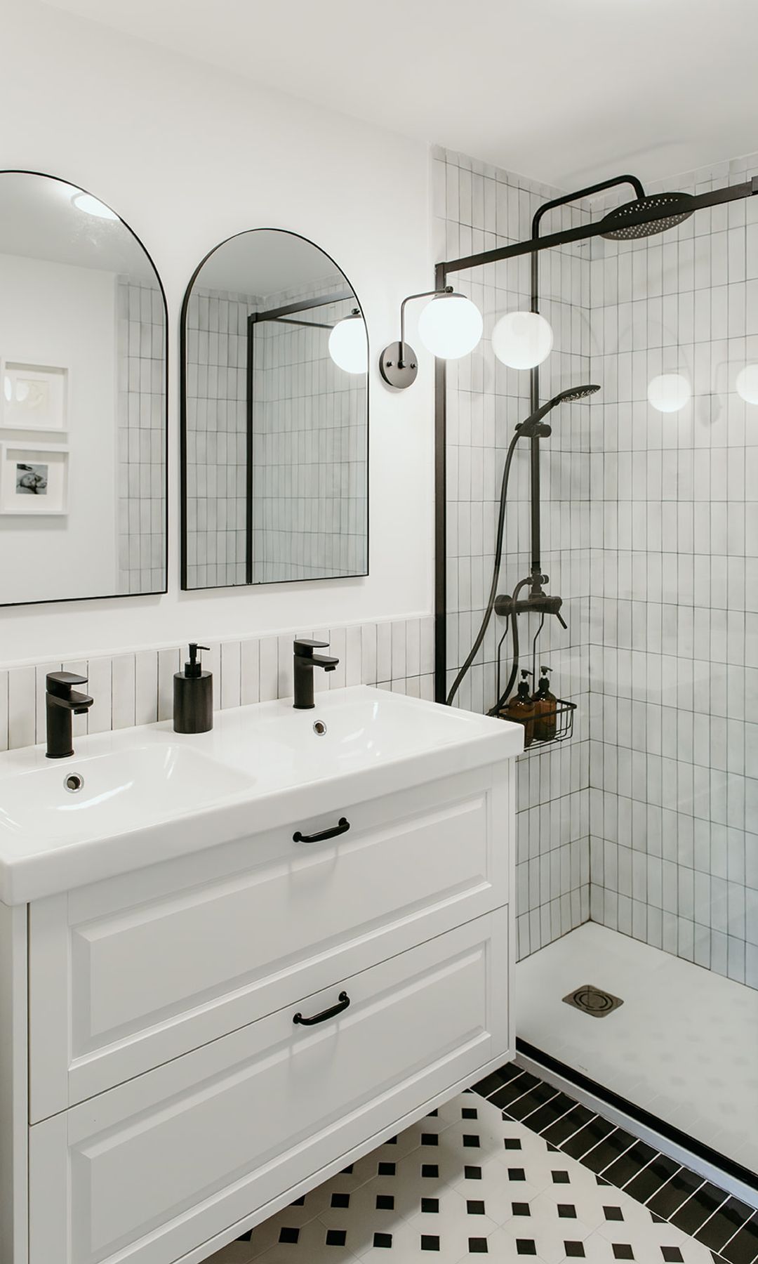 Baño en blanco y negro, con mueble blanco, mampara y griferías negras, espejos, alfombra