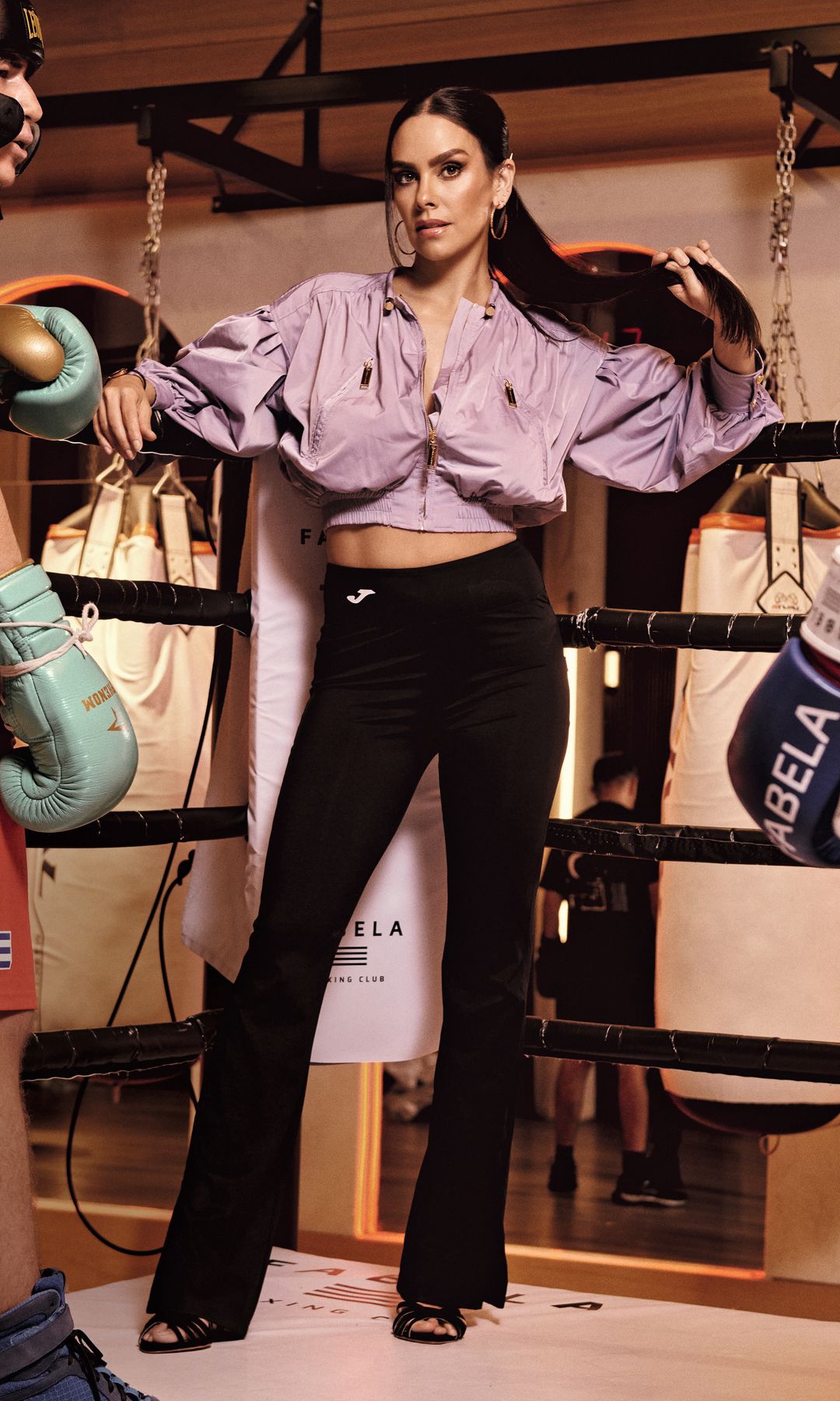 Cristina Pedroche en un ring de boxeo, con guantes y atuendo deportivo, rodeada de dos personas con cascos.